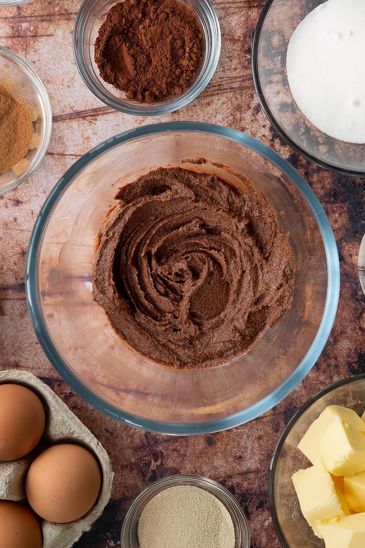 Overhead shot of butter, sugar, cinnamon and cocoa mixed together in a large clear bowl