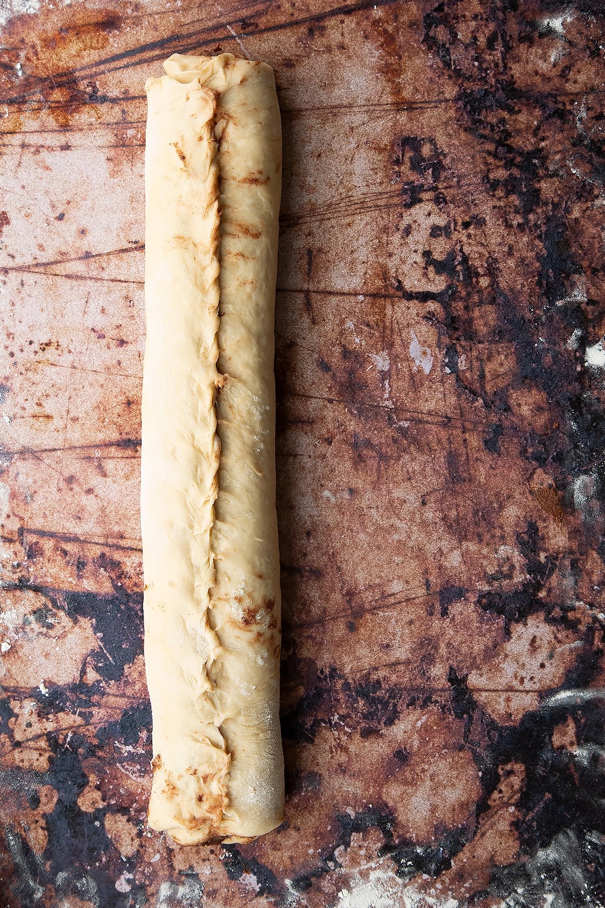 Overhead shot of dough layered with chocolate spread and rolled up into a sausage shape