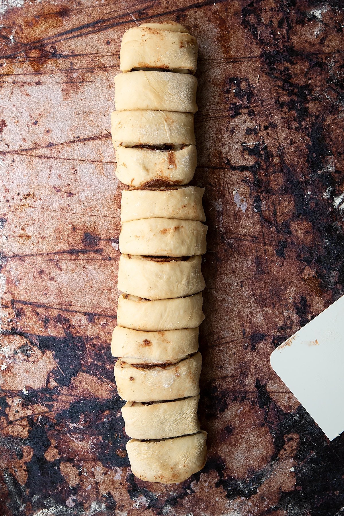 Overhead shot of dough layered with chocolate spread and rolled up into a sausage shape and cut into slices
