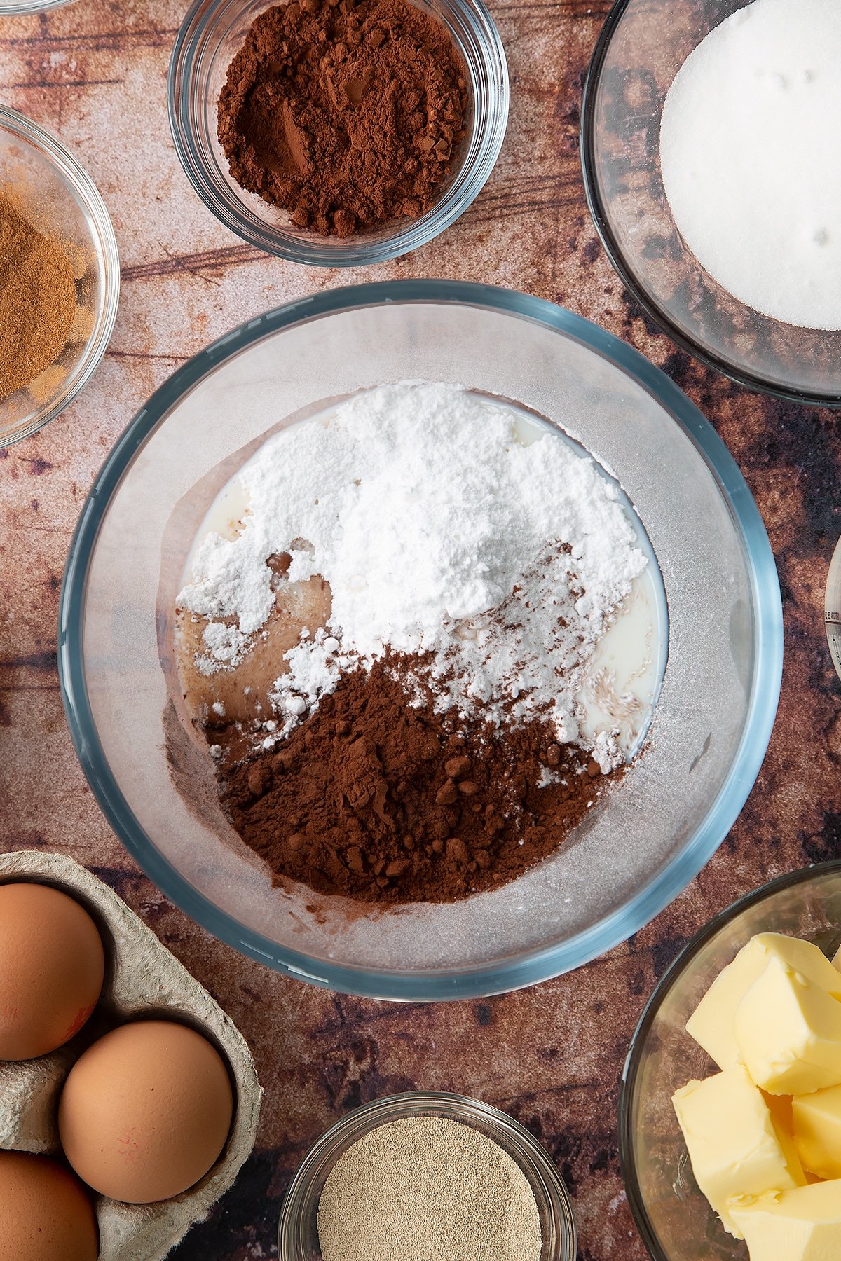 Overhead shot of icing sugar, milk and cocoa in a large clear bowl