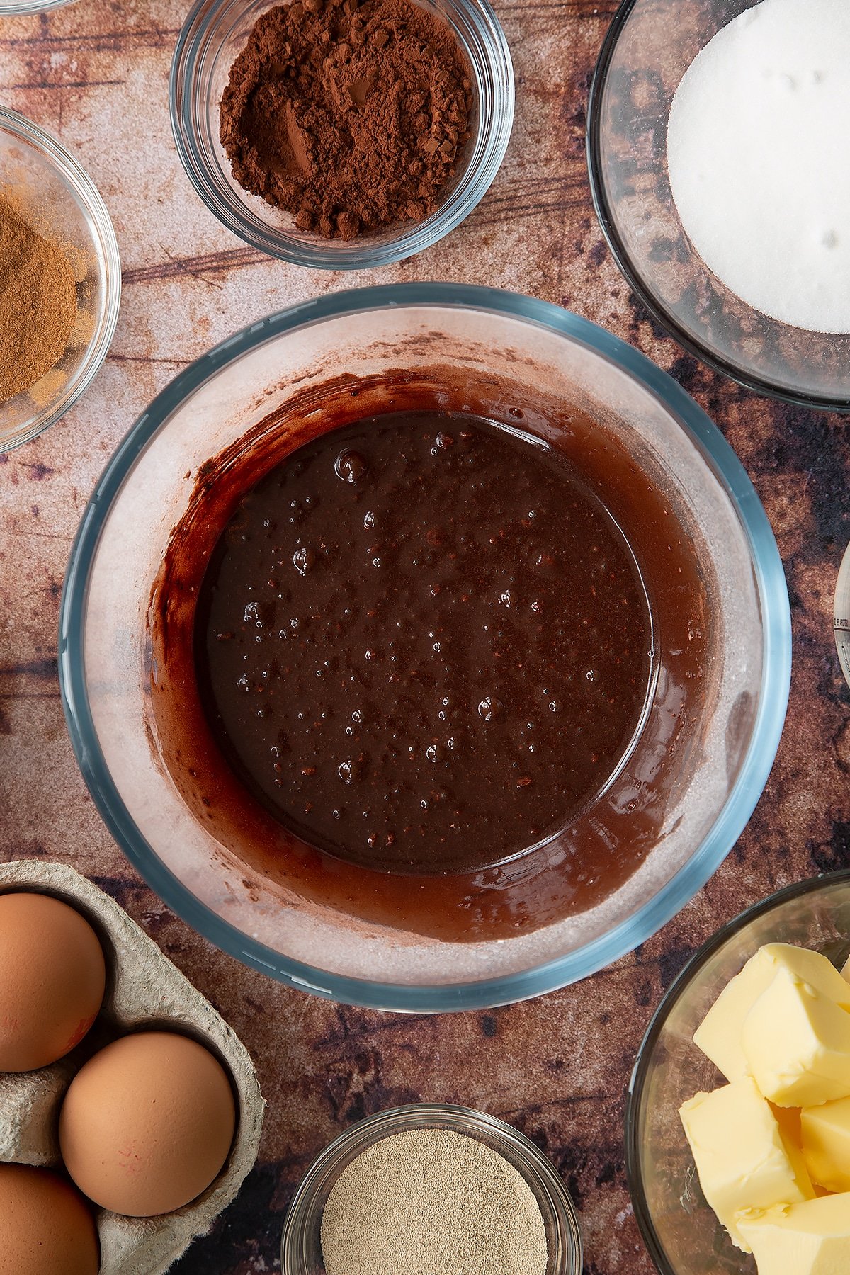 Overhead shot of cocoa, icing sugar and milk mixed in a large clear bowl