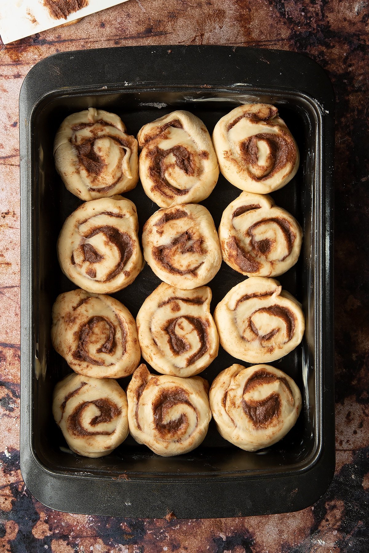 Overhead shot of dough rolled up into sections laid out in a deep baking tray