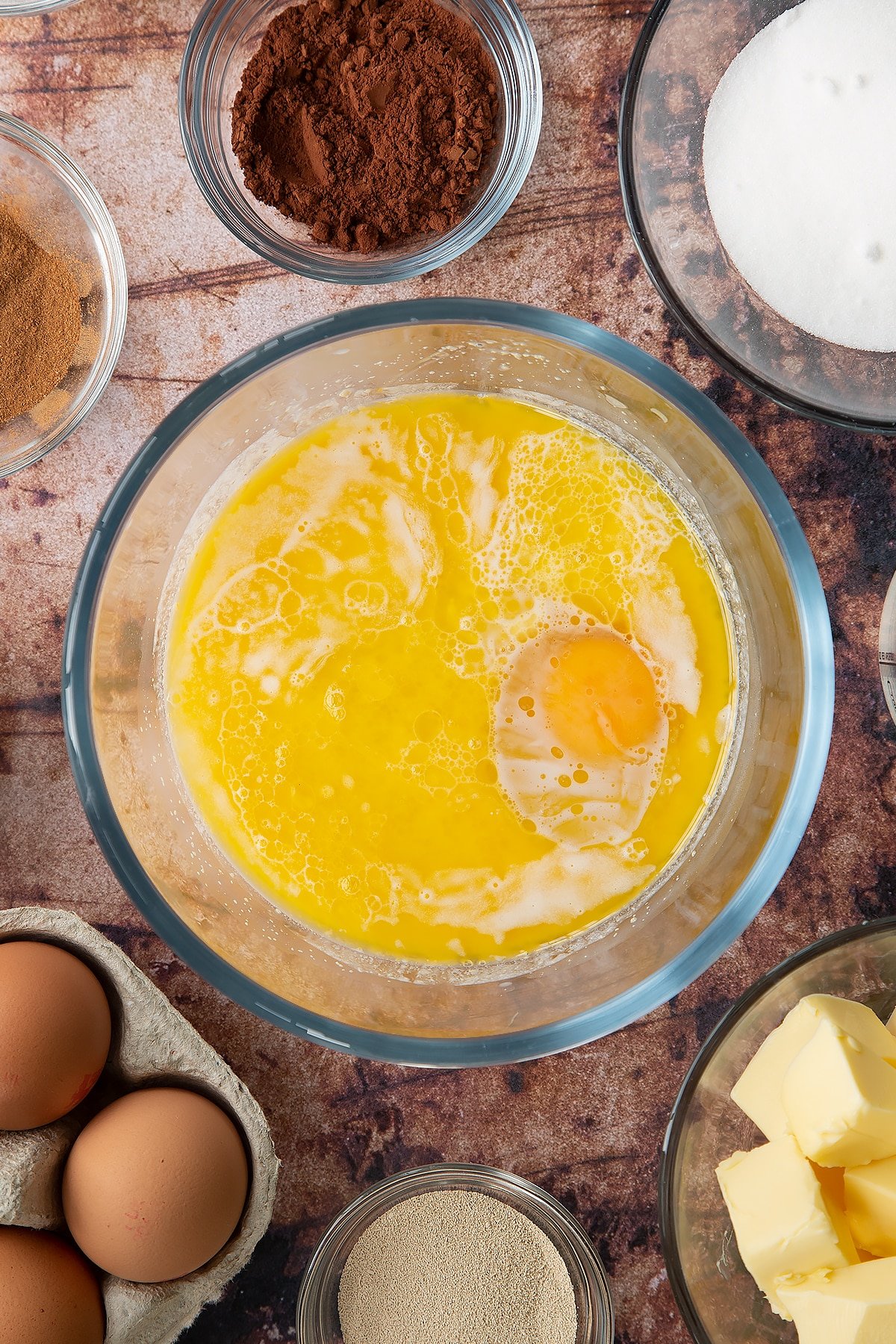 Overhead shot of milk mixture with egg and melted butter in a large clear bowl.