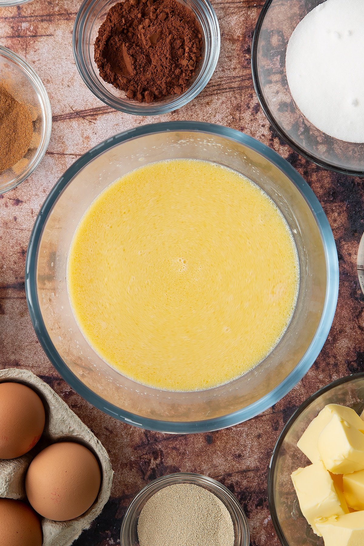 Overhead shot of milk mixes with butter and egg in a large clear bowl