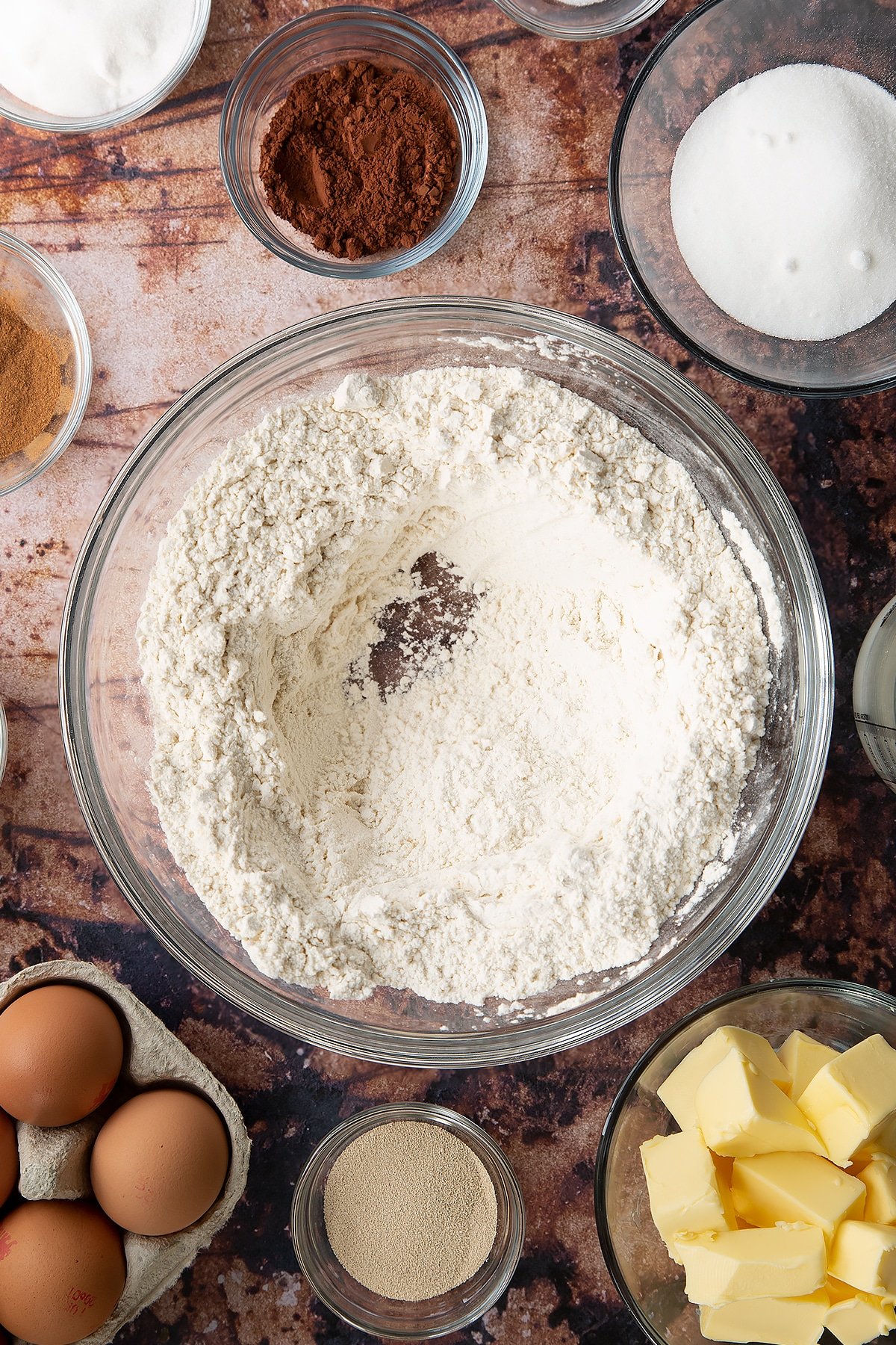 Overhead shot of flour and salt mixed and a well created in the middle in a large clear bowl