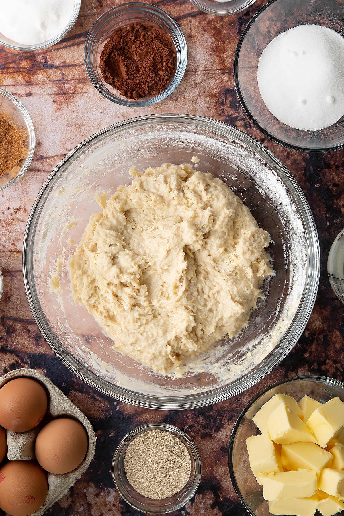 Overhead shot of sticky white dough forming in a large clear bowl