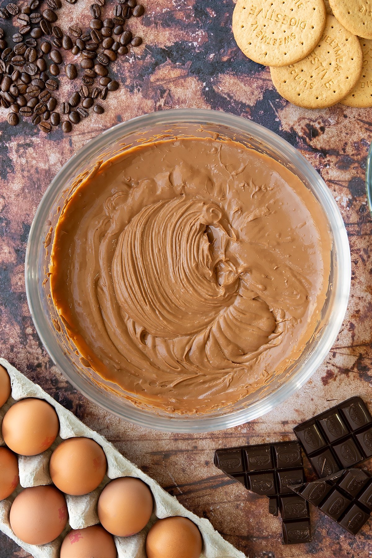 Over head shot of coffee chocolate cheesecake mix in a large clear bowl