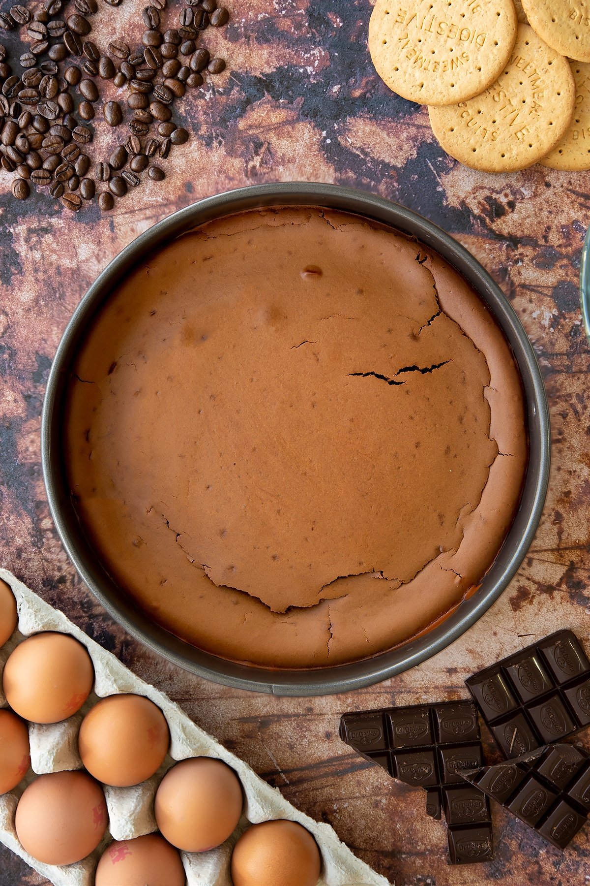 Overhead shot of baked coffee cheesecake in a large metal cake tin