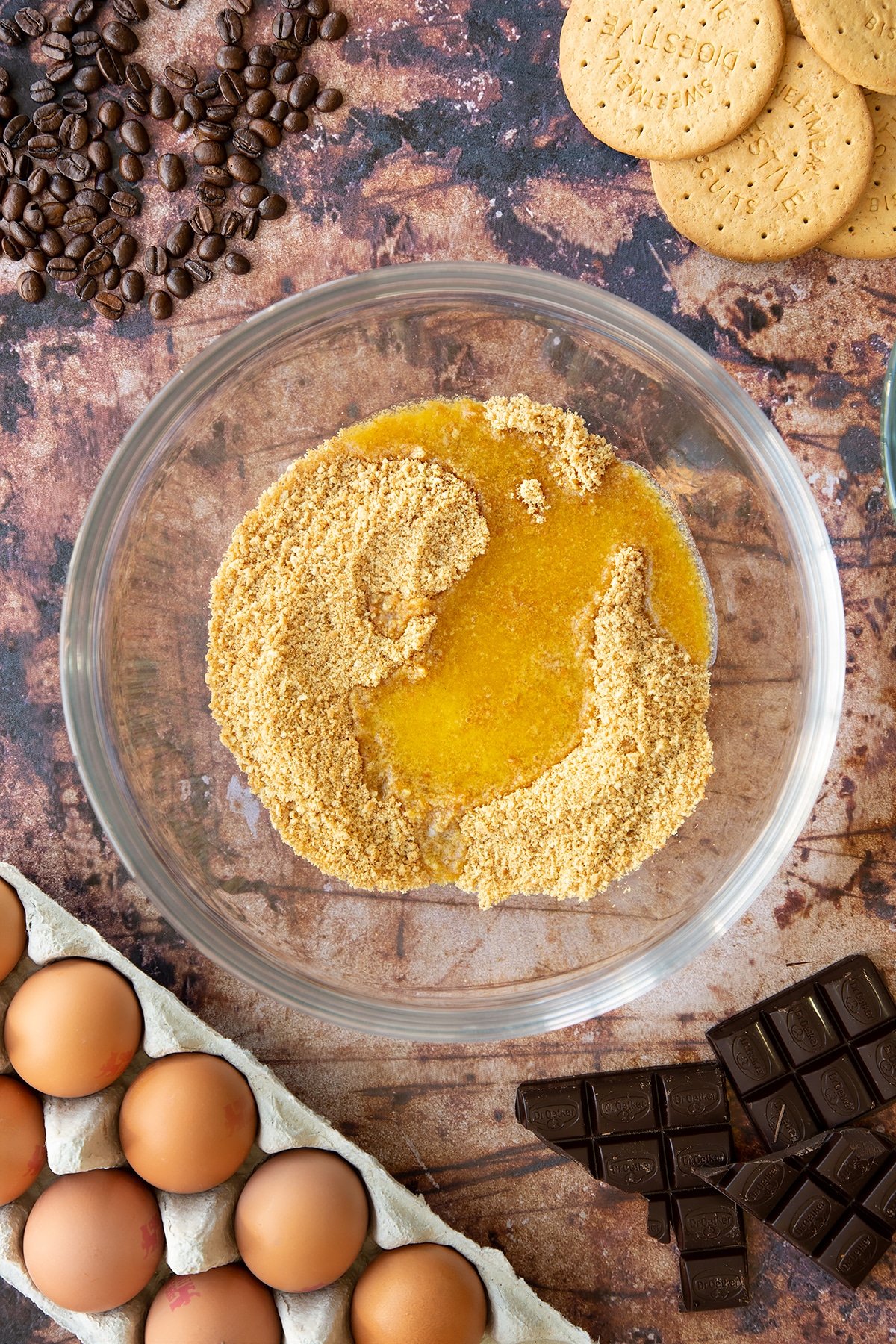 Overhead shot of digestive biscuits crumb covered with melted butter in a large clear bowl