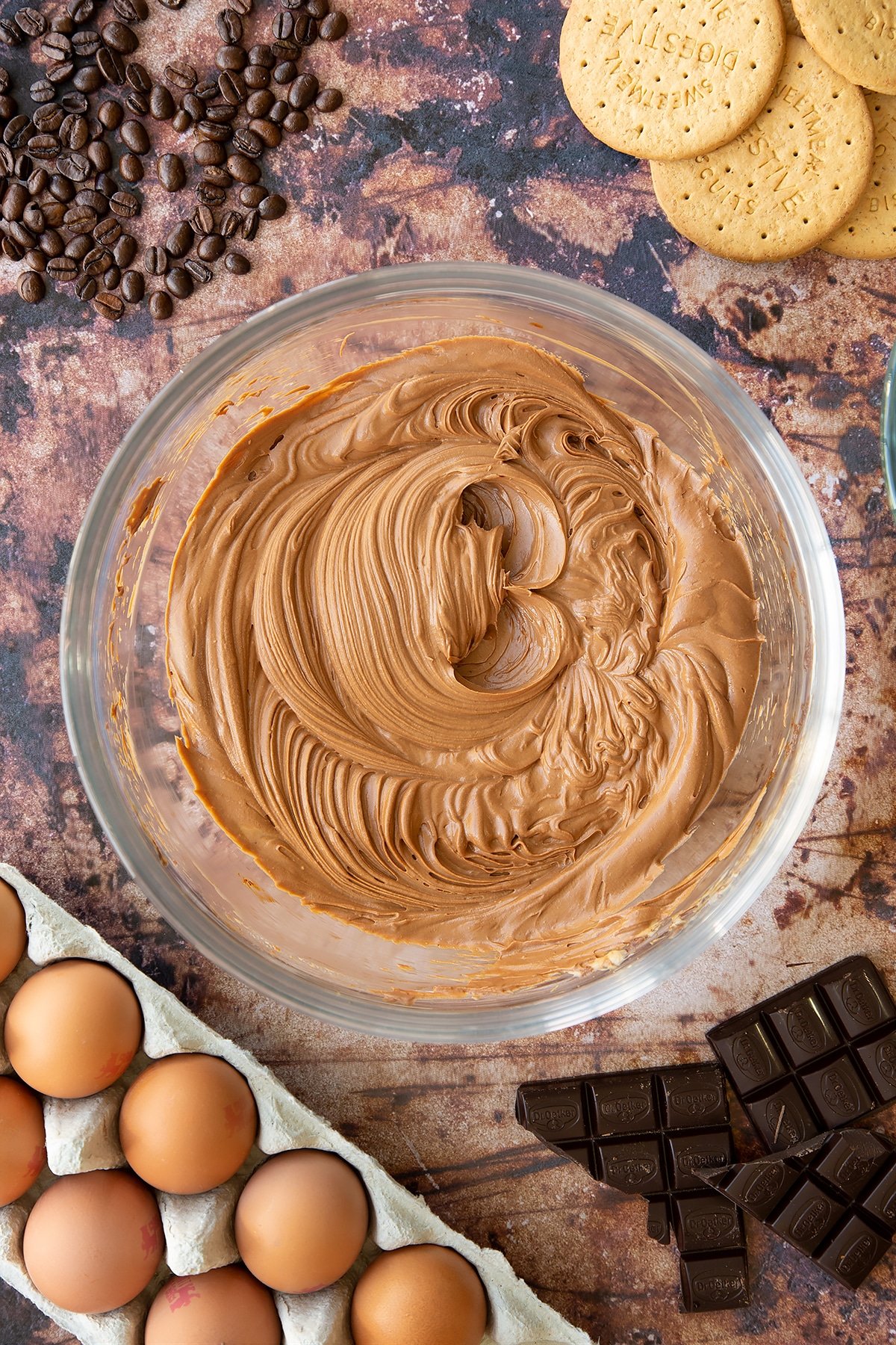 Overhead shot of cream cheese, coffee and chocolate mix whisked together in a large clear bowl