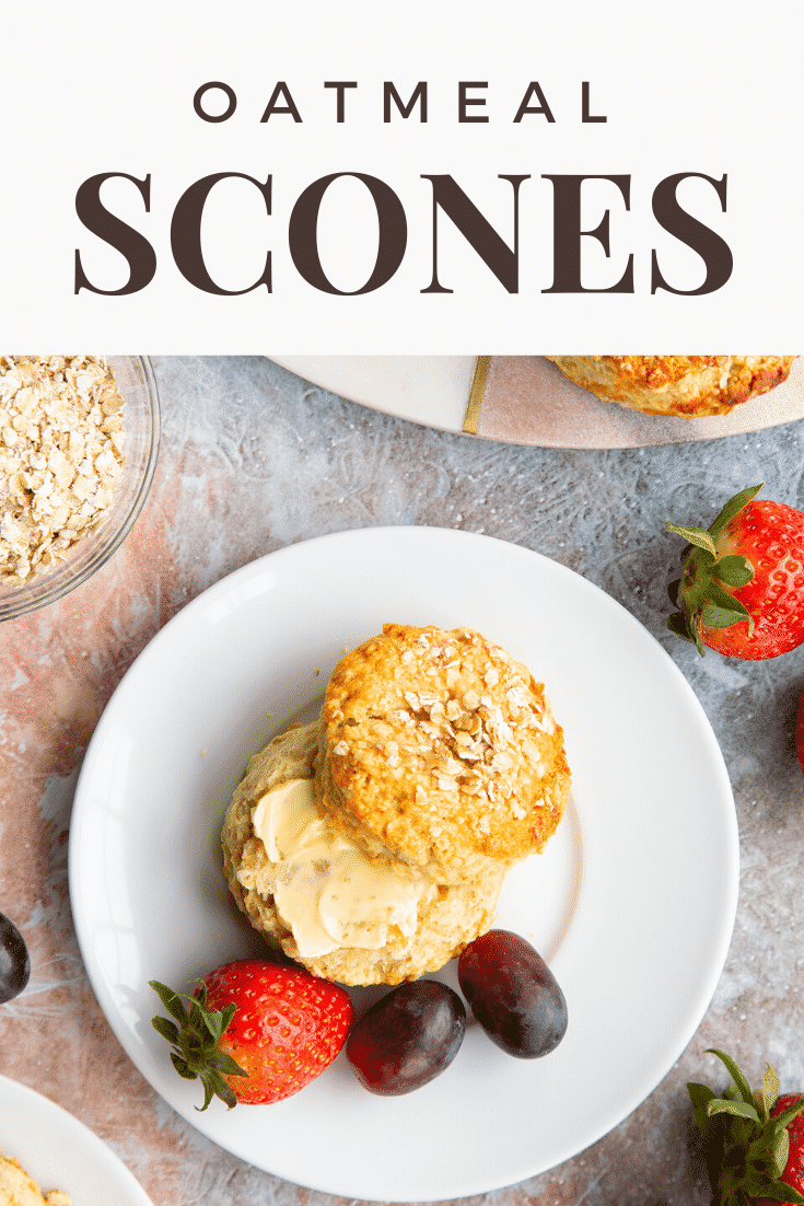 Oatmeal scone on a white plate, shown from above. It has been split and buttered. Caption reads: Oatmeal Scones