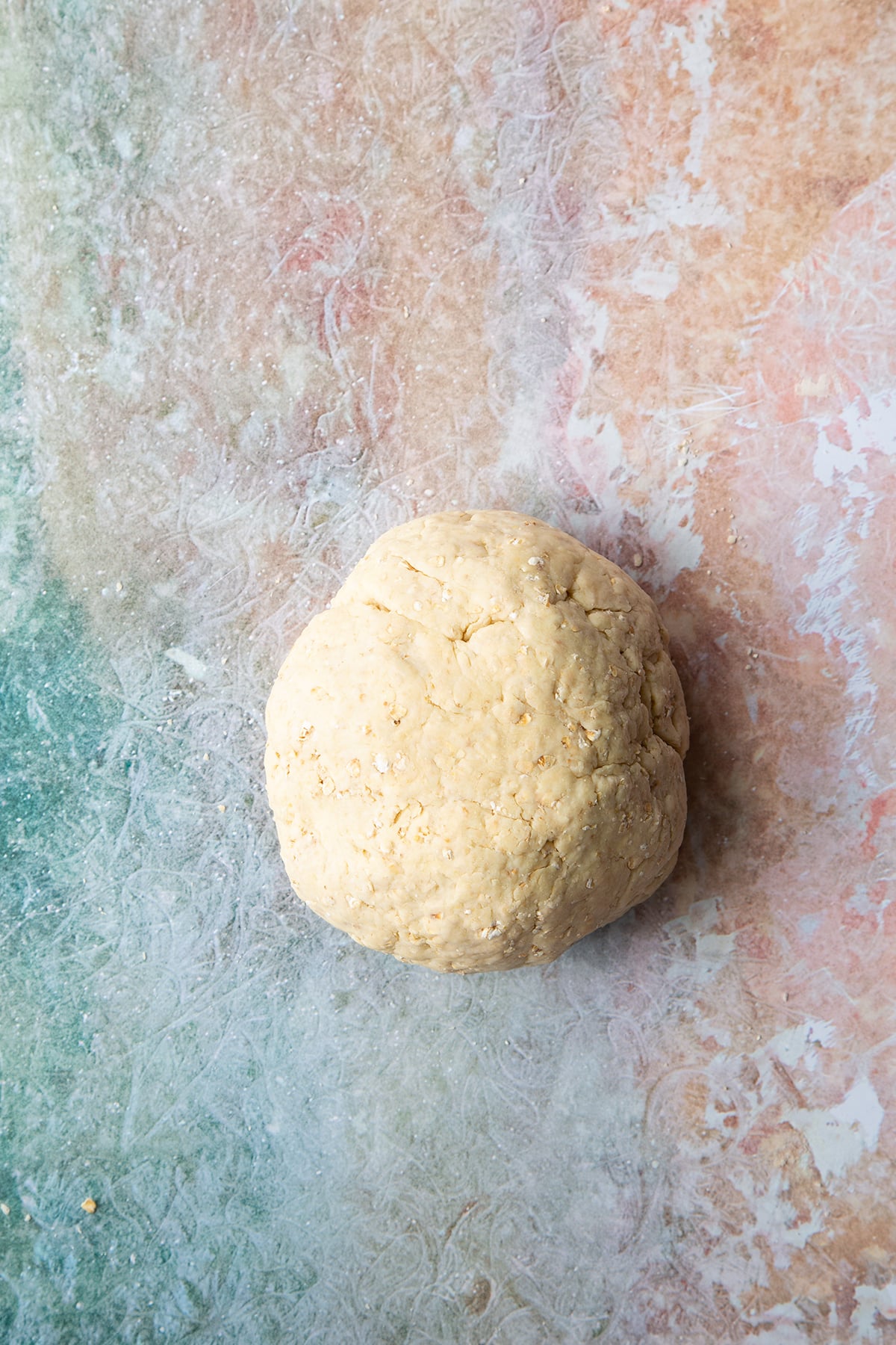 A ball of oatmeal scone dough on a clean surface.