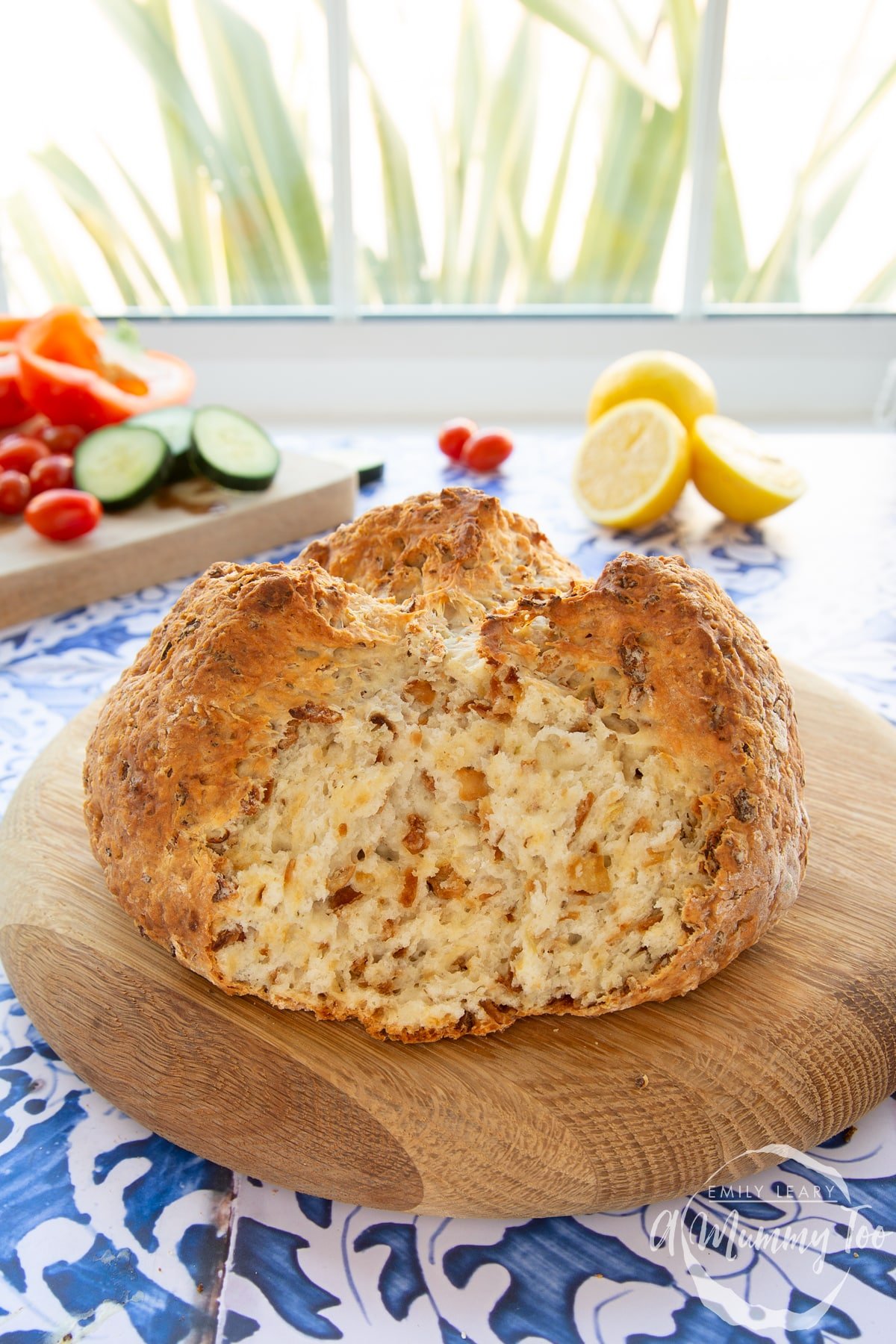 A loaf of onion soda bread on a wooden board. A piece has been torn off.