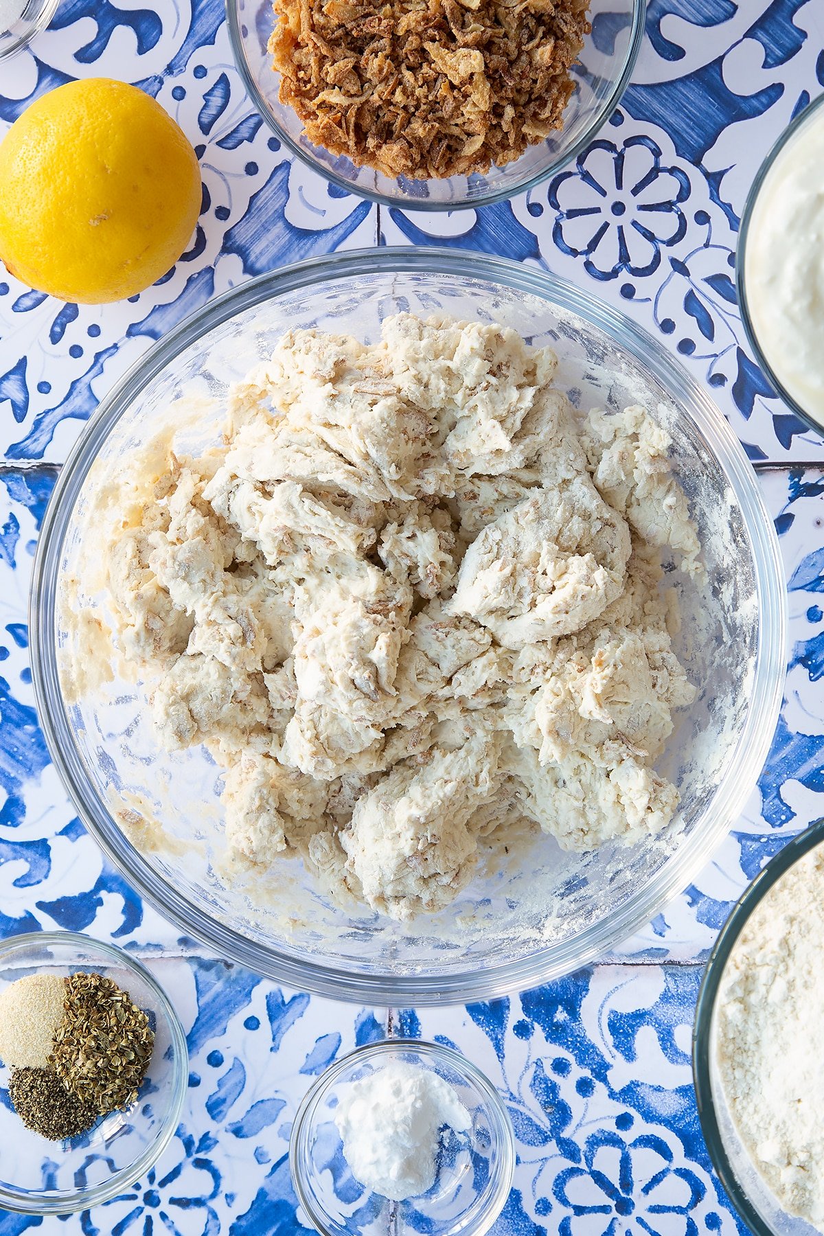 Roughly mixed onion soda bread dough in a mixing bowl. Ingredients to make onion soda bread surround the bowl.