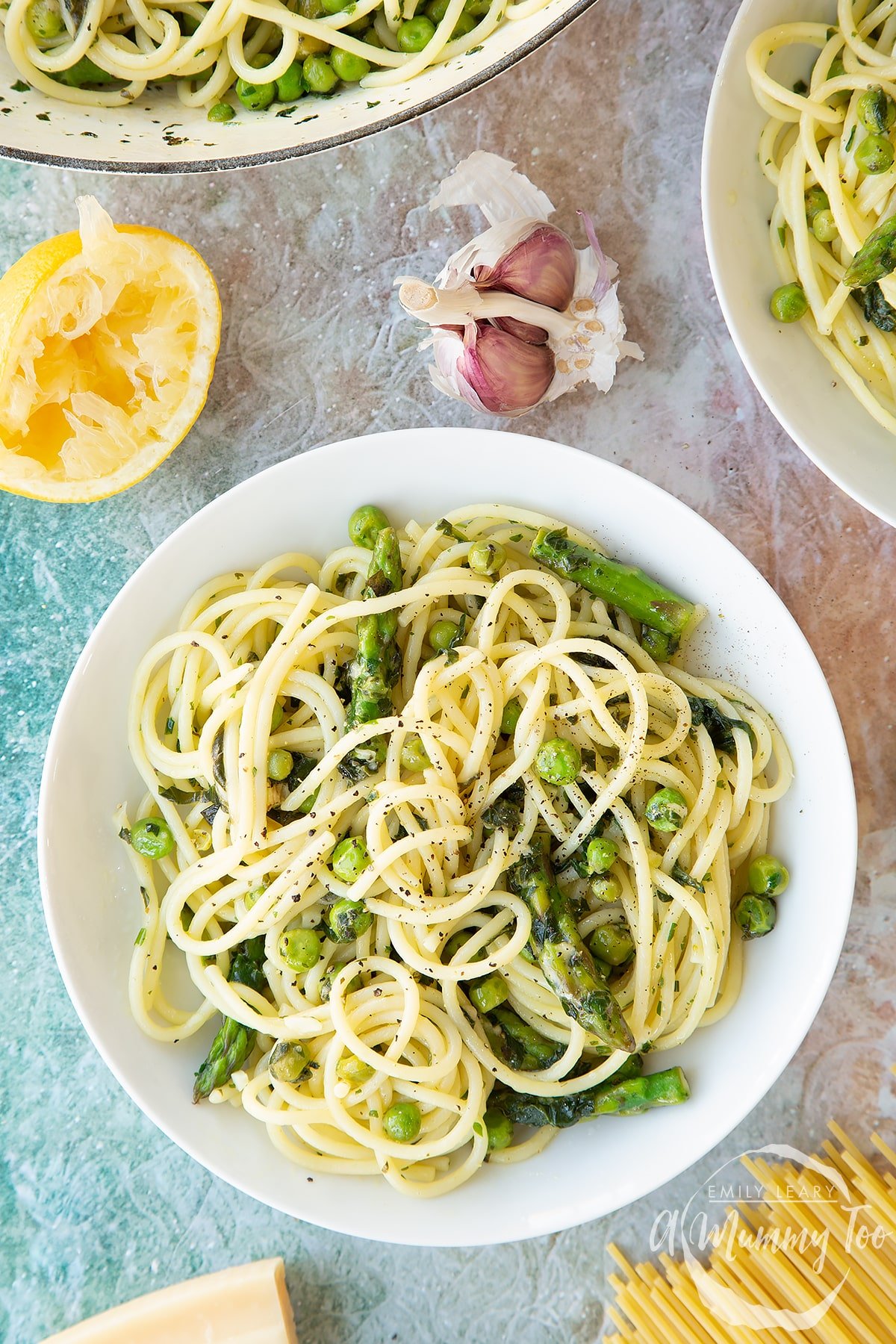 Summer spaghetti with spinach, basil, asparagus and peas, served in a white bowl. Shown from above.