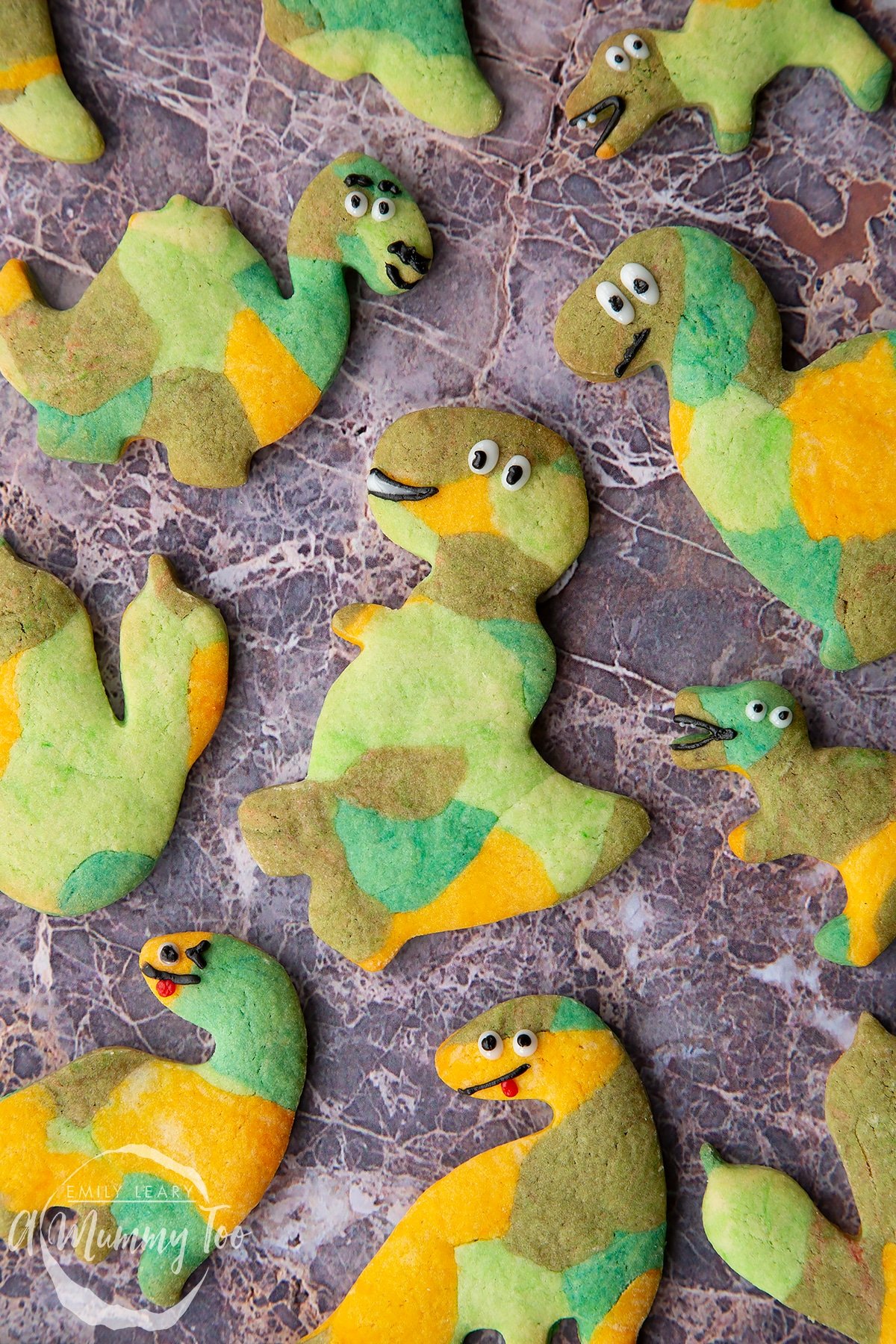 Overhead shot of green dinosaur cookies with the A Mummy Too logo in the corner