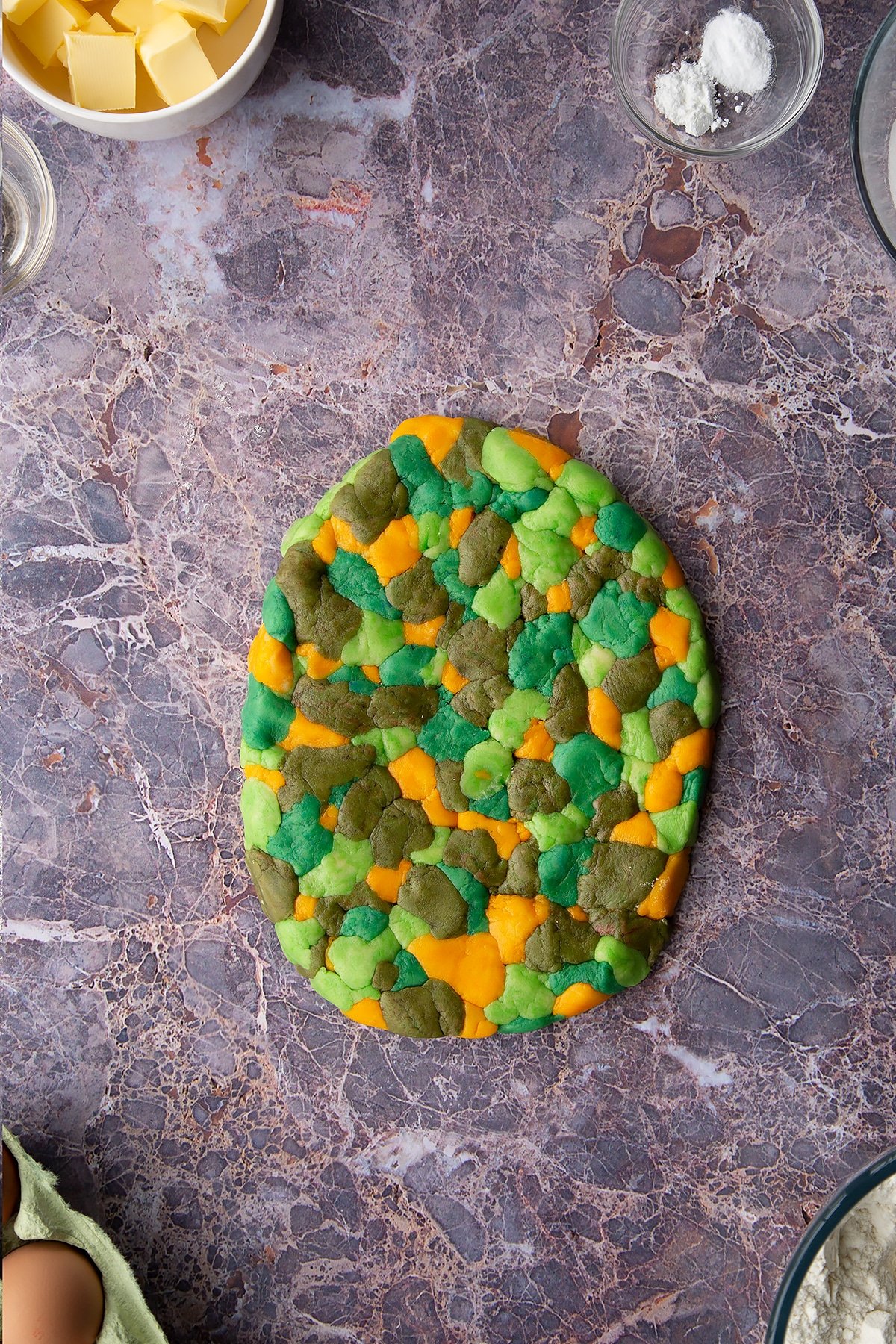 Overhead shot of small chunks of coloured cookie dough pieces laid out together on a surface combines together