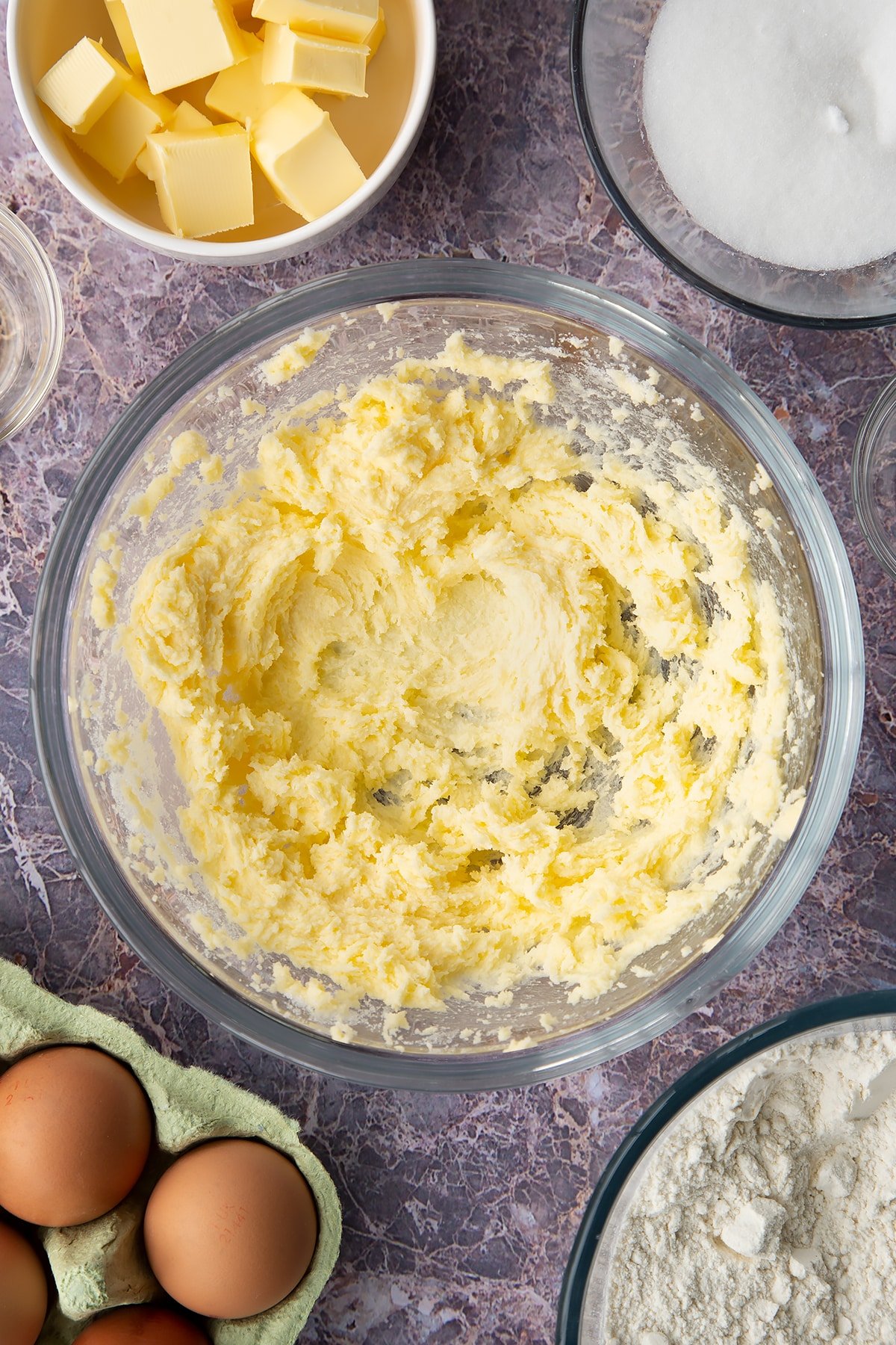 Overhead shot of butter creamed with sugar in a large clear bowl