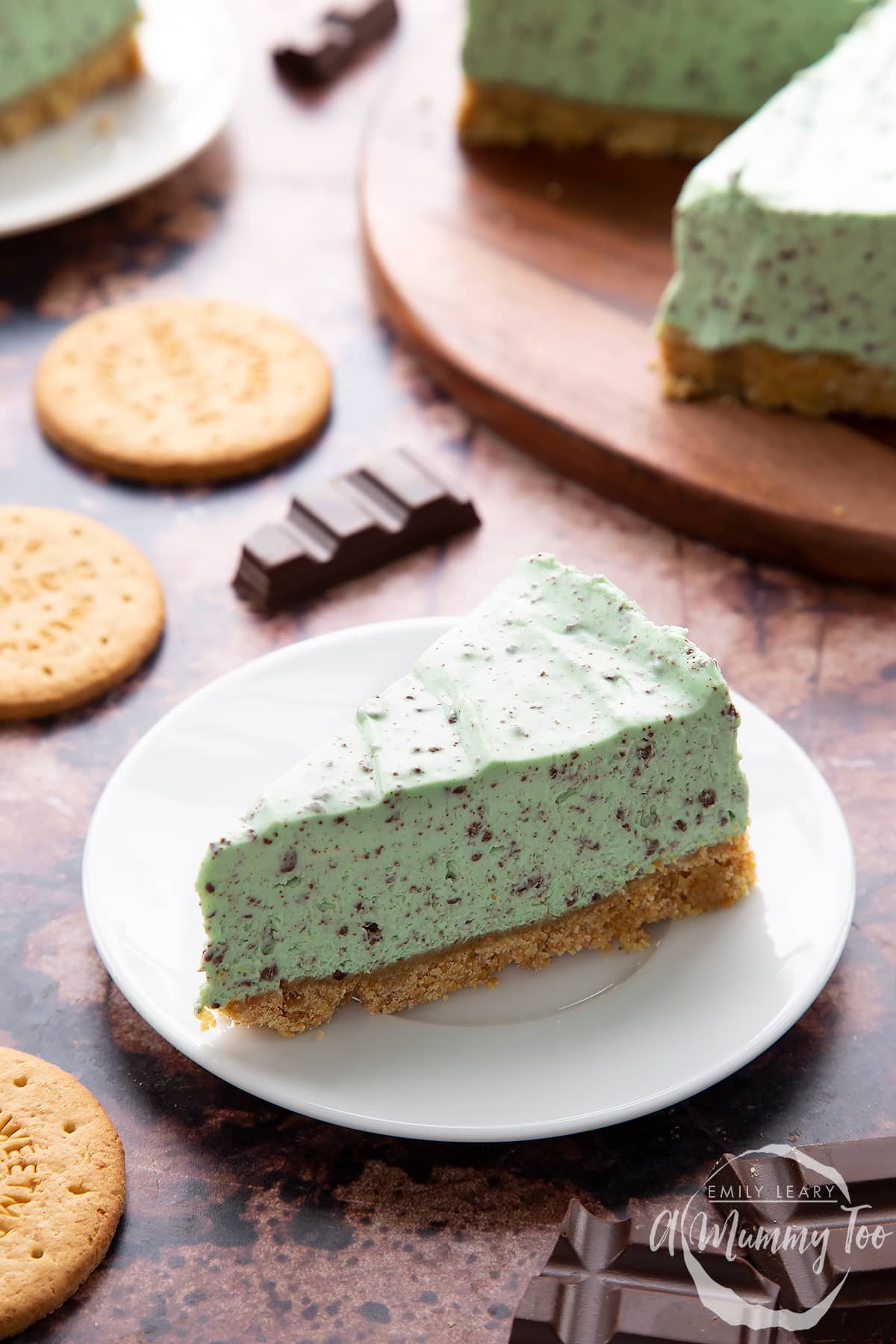 A slice of no bake mint cheesecake with a biscuit base on a white plate. 