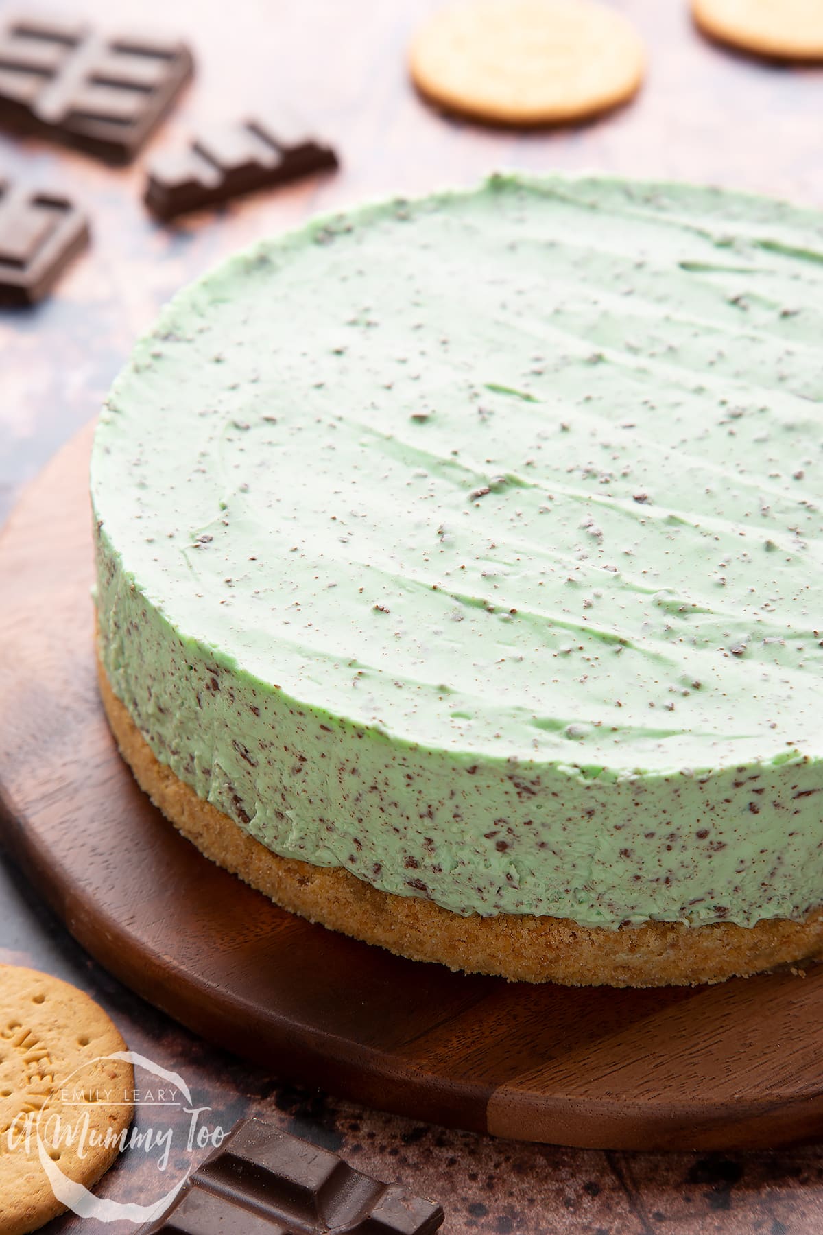 No bake mint cheesecake with a biscuit base on a wooden board.