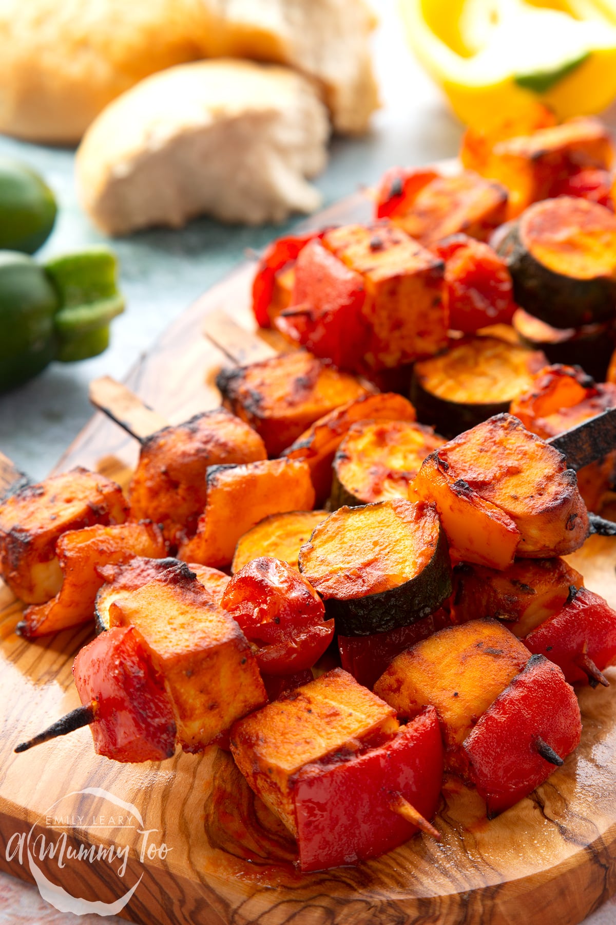 Tofu skewers piled on a wooden board.