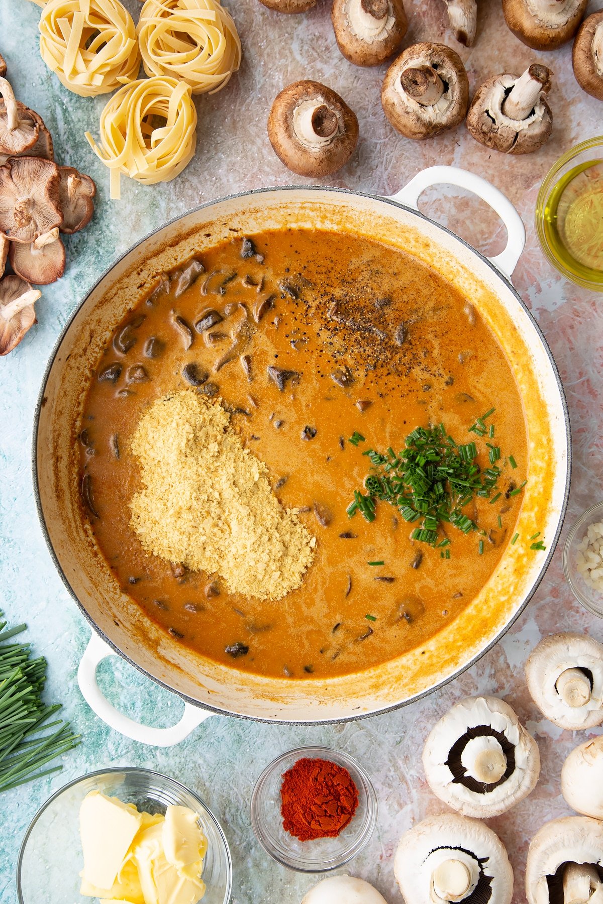 sauteed mushrroms with added coconut cream, paprika, coconut milk and chives in a large white pan. 