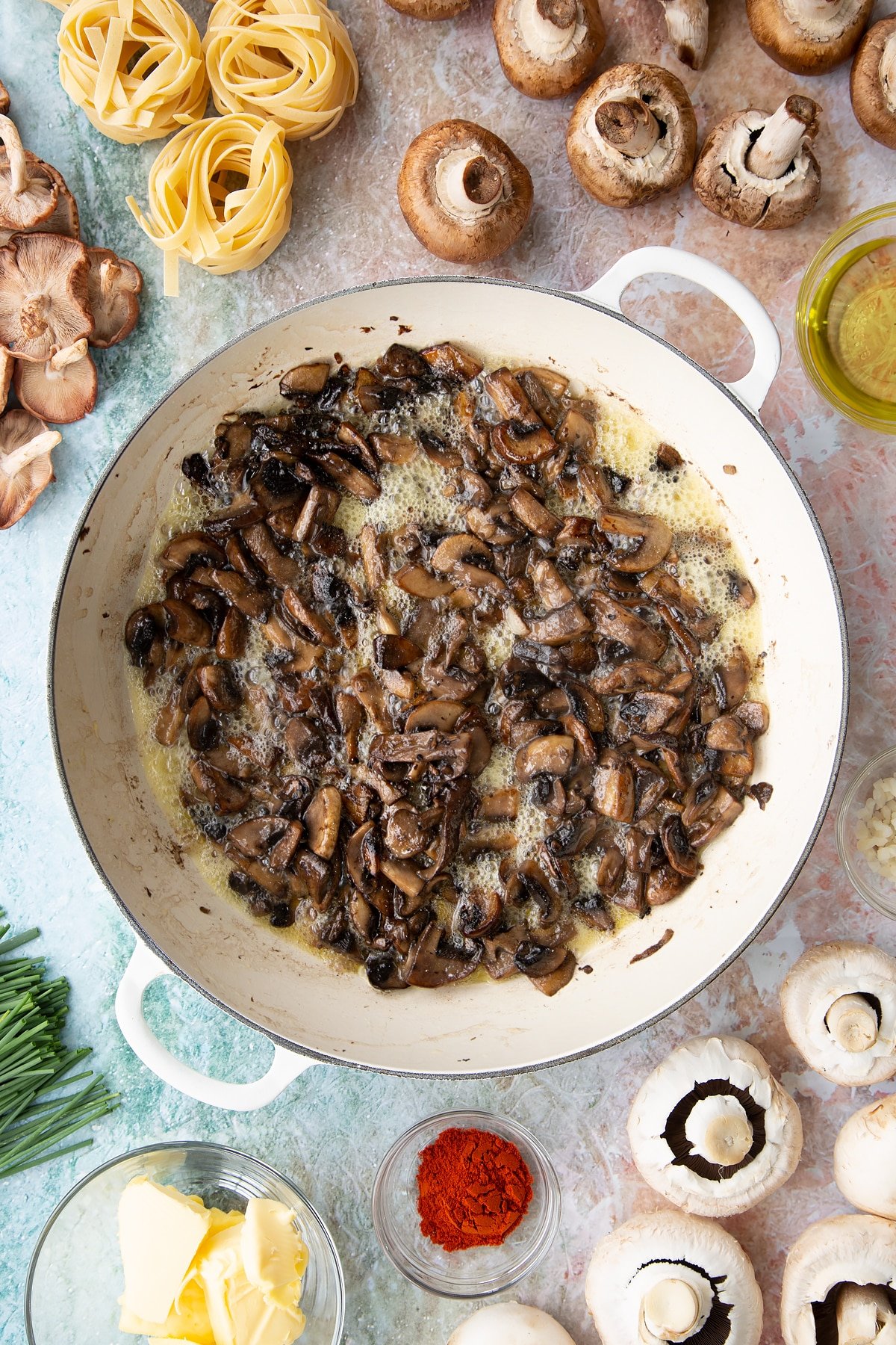sauteed mushrroms in butter and garlic in a large white pan.