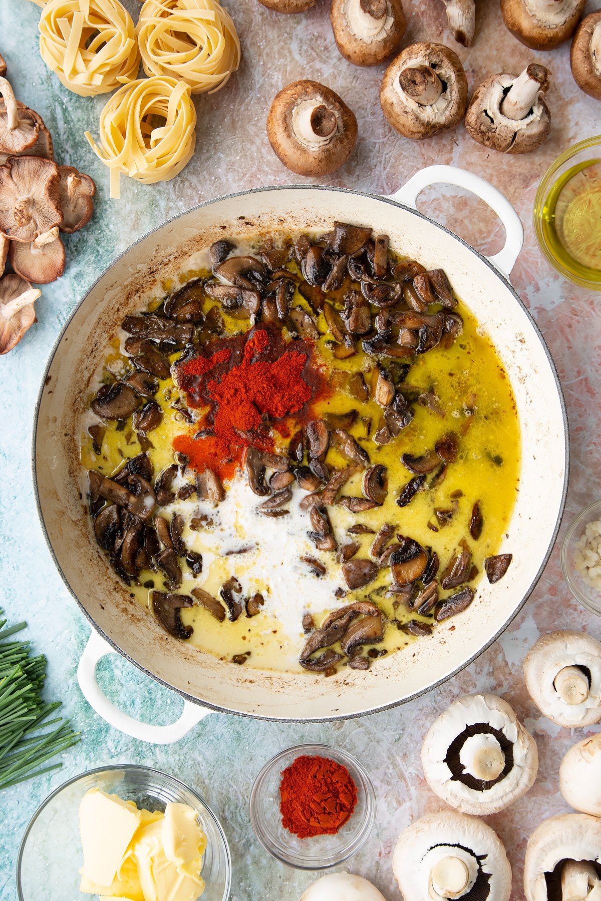 sauteed mushrroms with added coconut cream, paprika, coconut milk and stock in a large white pan. 