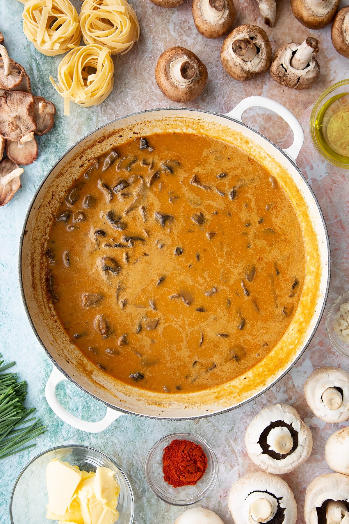 mushrroms with added coconut cream, paprika, coconut milk and stock sauce in a large white pan.