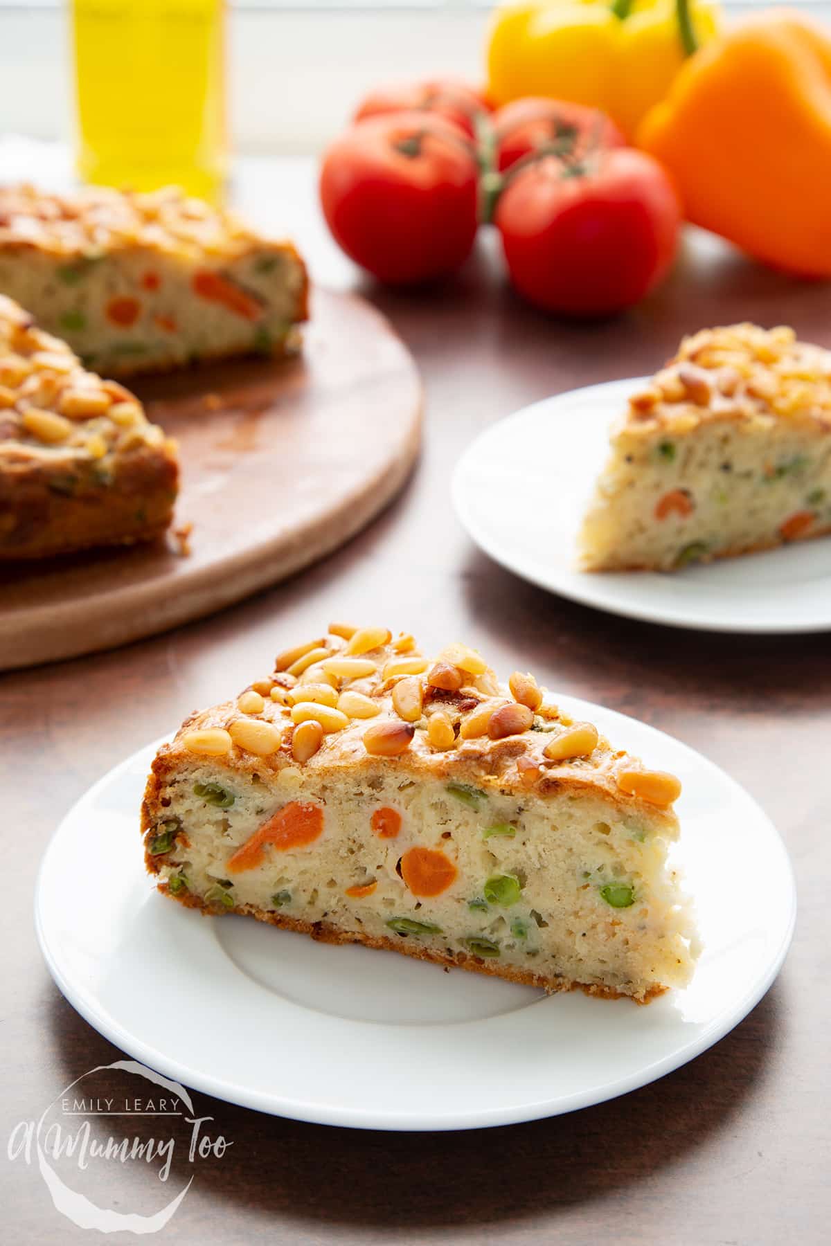 A slice of vegetable cake on a white plate with more cake in the background. 