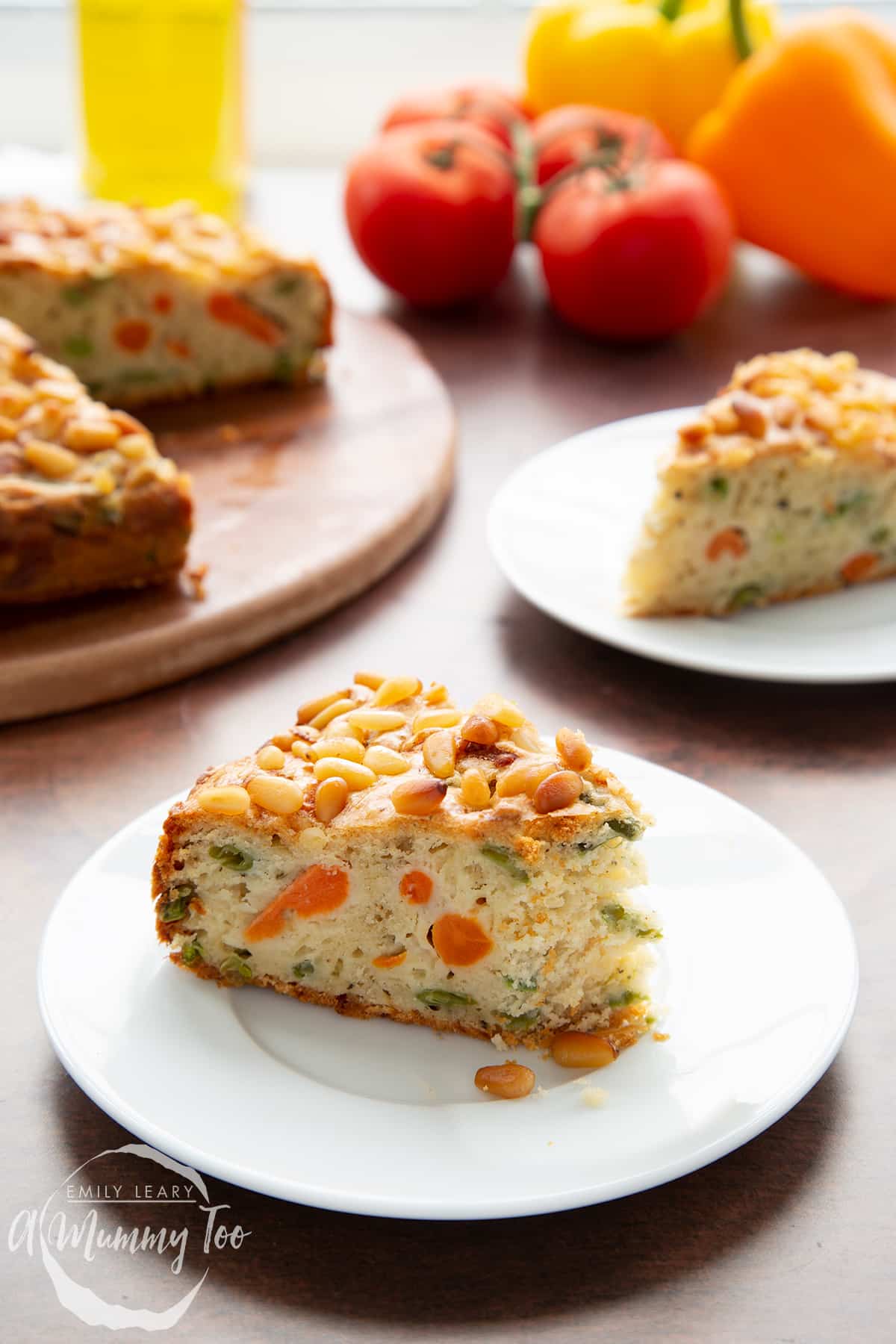 A slice of vegetable cake on a white plate with more cake in the background. A piece has been eaten.