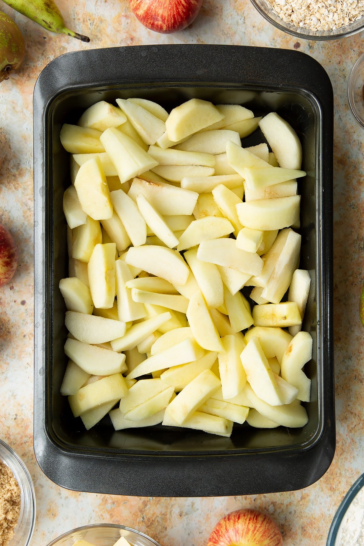 Peeled apple and pear wedges in a greased tray.