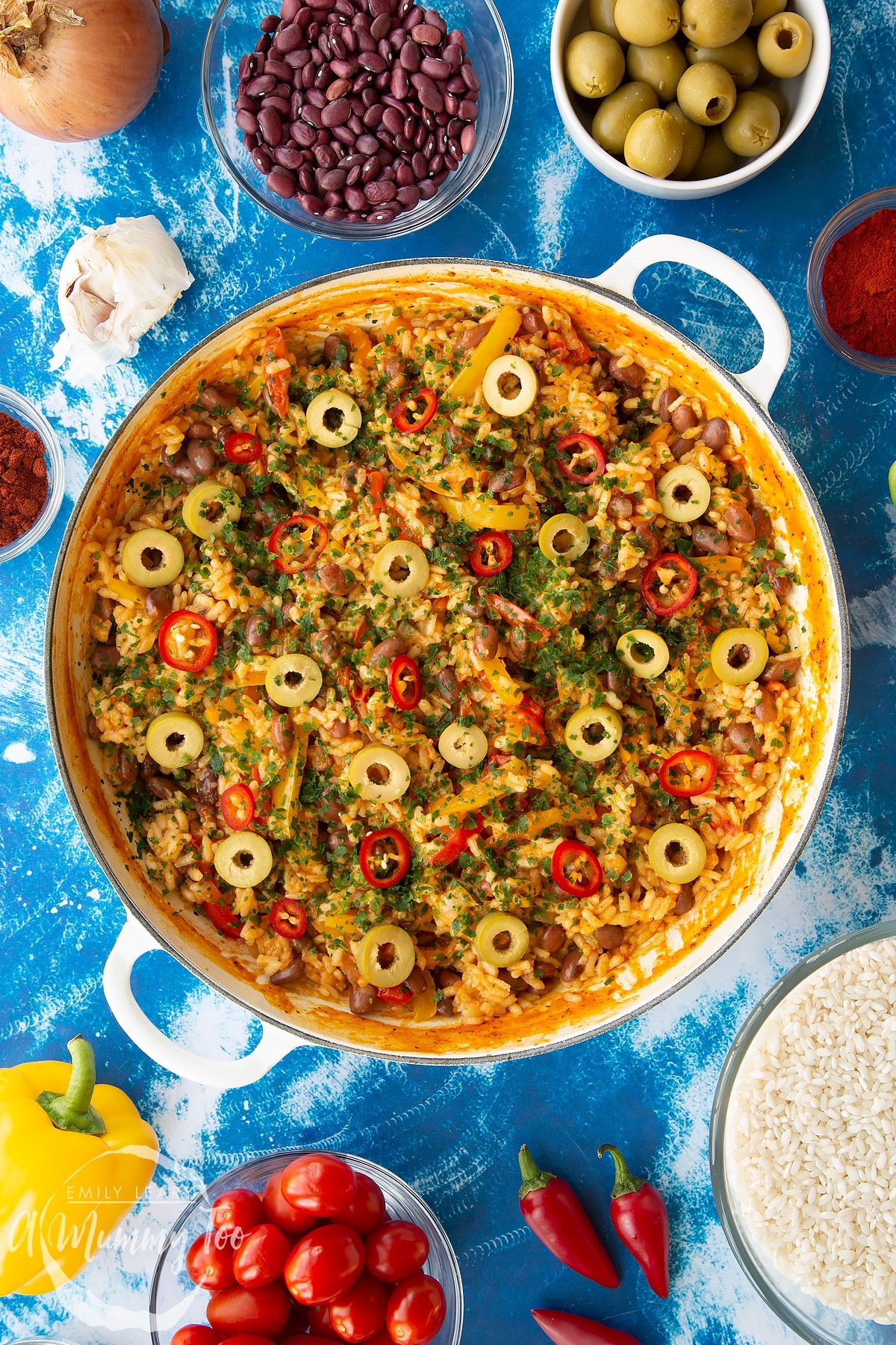 Easy Spanish rice and beans in a large shallow pot, garnished with olives, chilli and parsley.