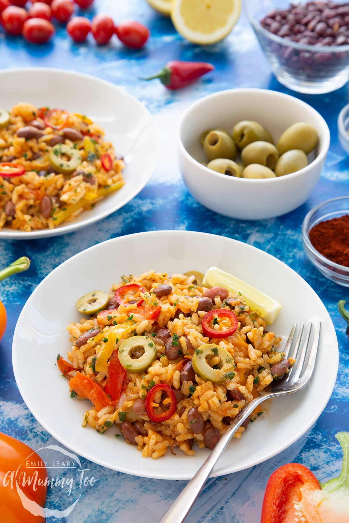 Easy Spanish rice and beans served to a shallow white bowl with a fork.