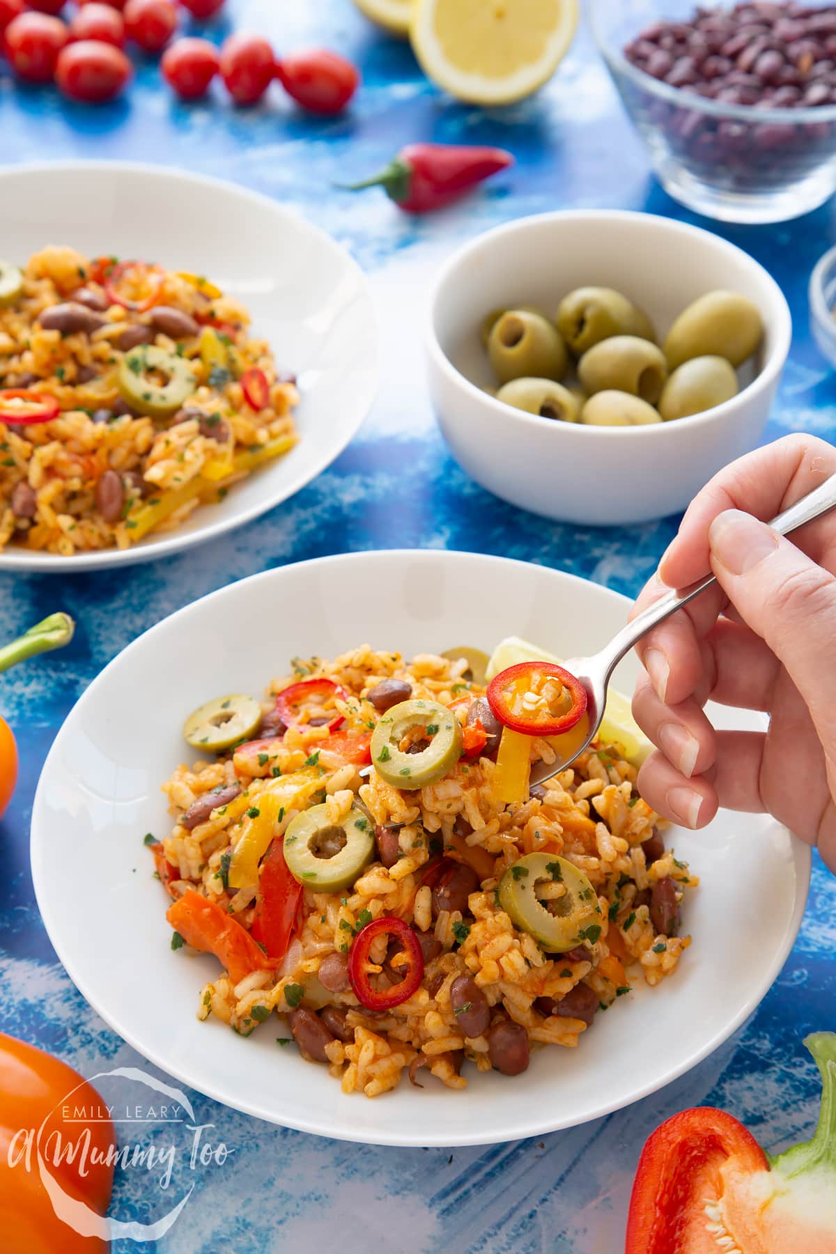 Easy Spanish rice and beans served to a shallow white bowl. A fork digs in to take some.