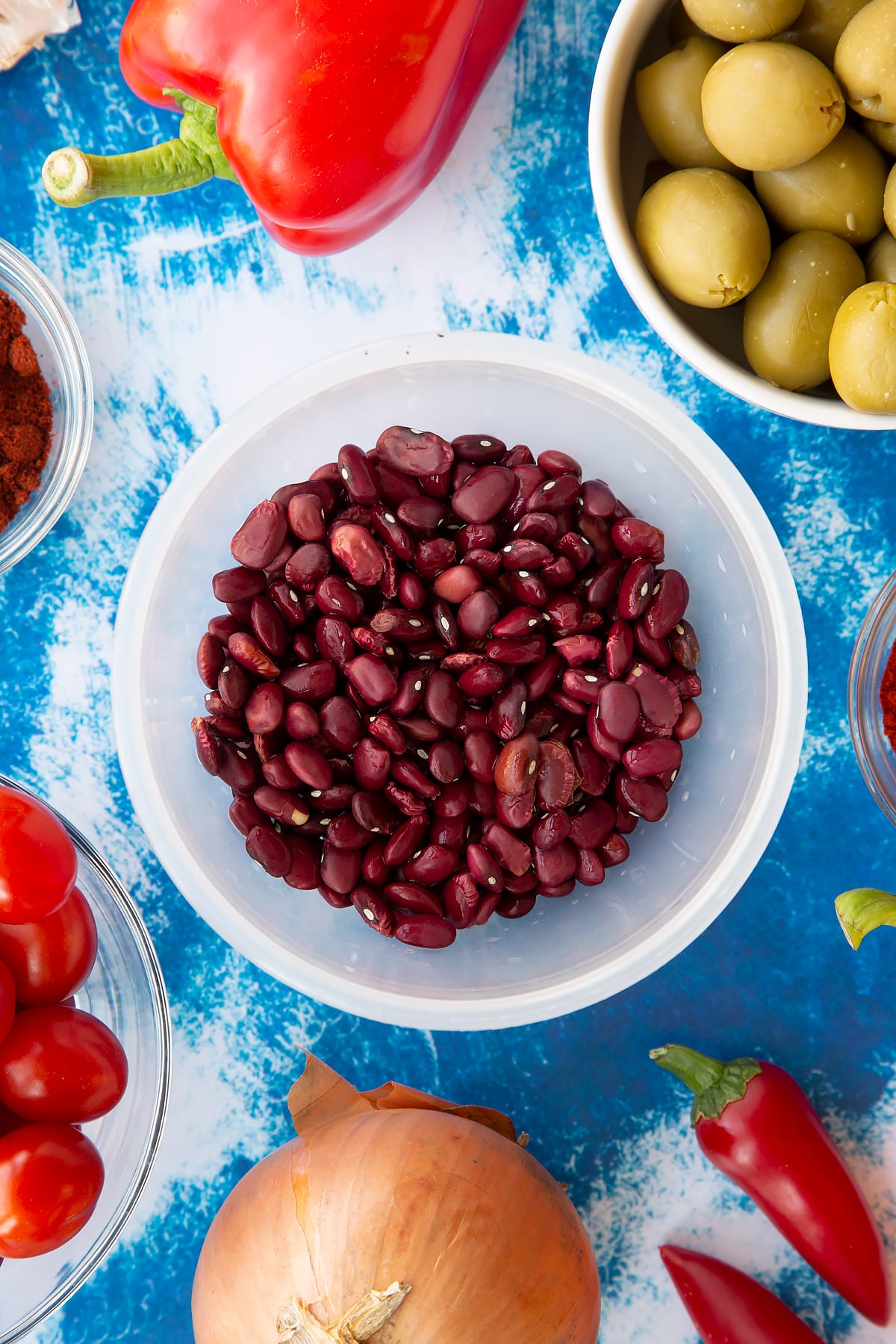 Dried kidney beans in a small pot. Ingredients to make easy Spanish rice and beans surround the pot.