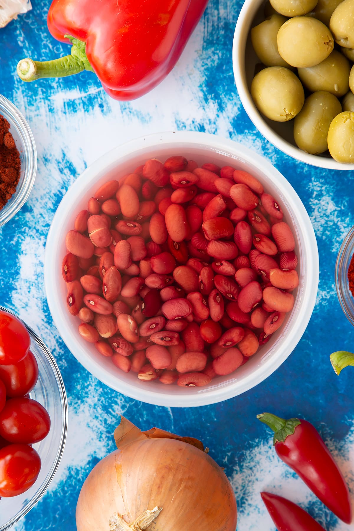 Soaked kidney beans in a small pot. Ingredients to make easy Spanish rice and beans surround the pot.