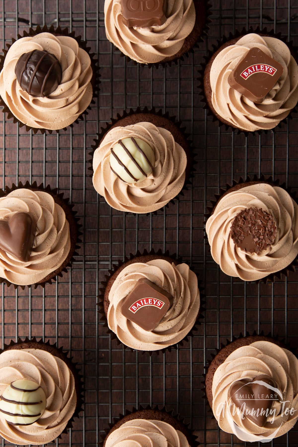 Baileys chocolate cupcakes topped with Baileys icing and a Baileys chocolate. Shown from above on a wire cooling rack.