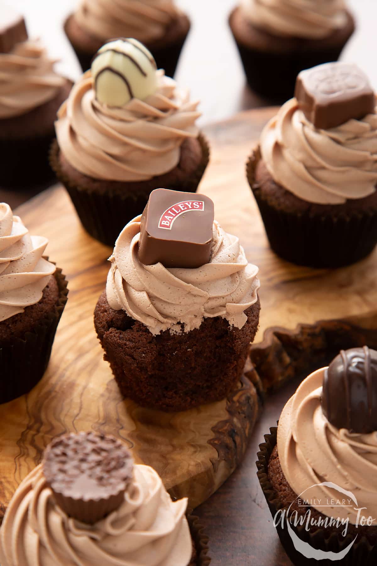 Baileys chocolate cupcakes topped with Baileys icing and a Baileys chocolate. A bite has been taken from one,