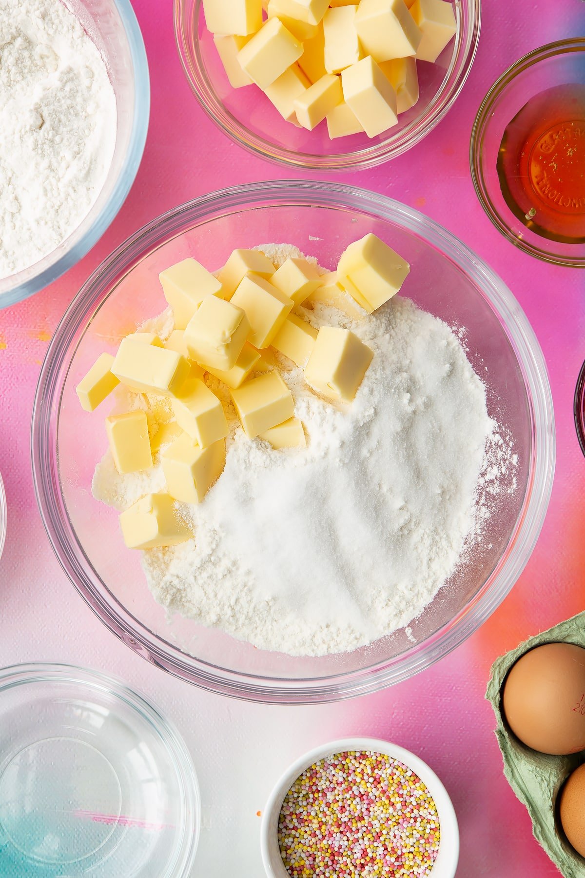 Butter, gluten free flour and sugar in a glass mixing bowl. Ingredients to make gluten free pop tarts surround the bowl.