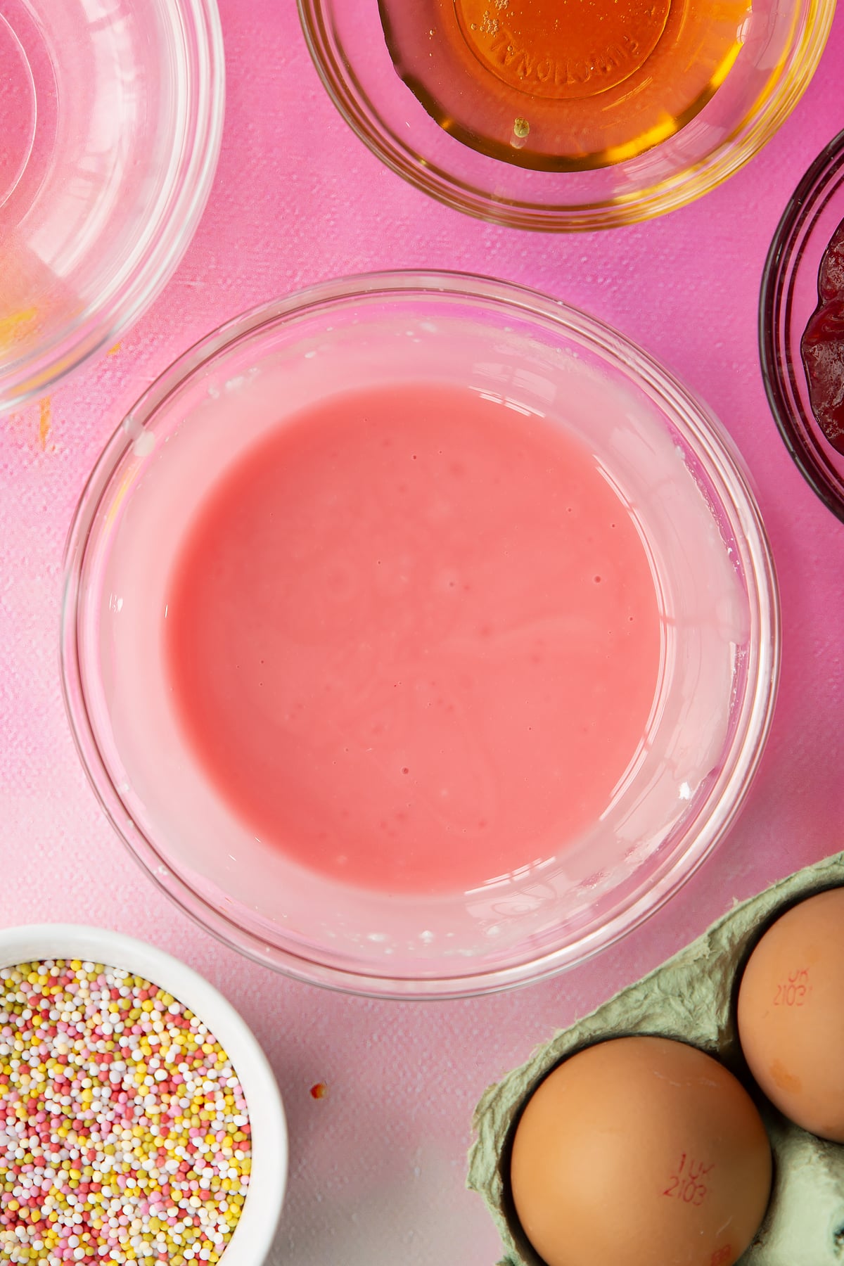 Pink icing in a small bowl. Ingredients to make gluten free pop tarts surround the bowl.