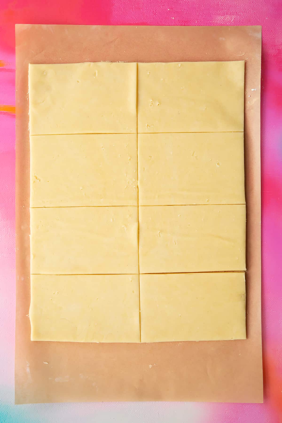 A neat rectangle of gluten free pasty rolled out on a sheet of baking paper and cut into eight pieces.