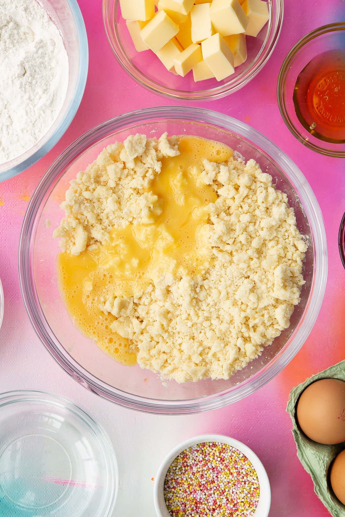 Butter, gluten free flour and sugar rubbed together in a glass mixing bowl with eggs on top. Ingredients to make gluten free pop tarts surround the bowl.