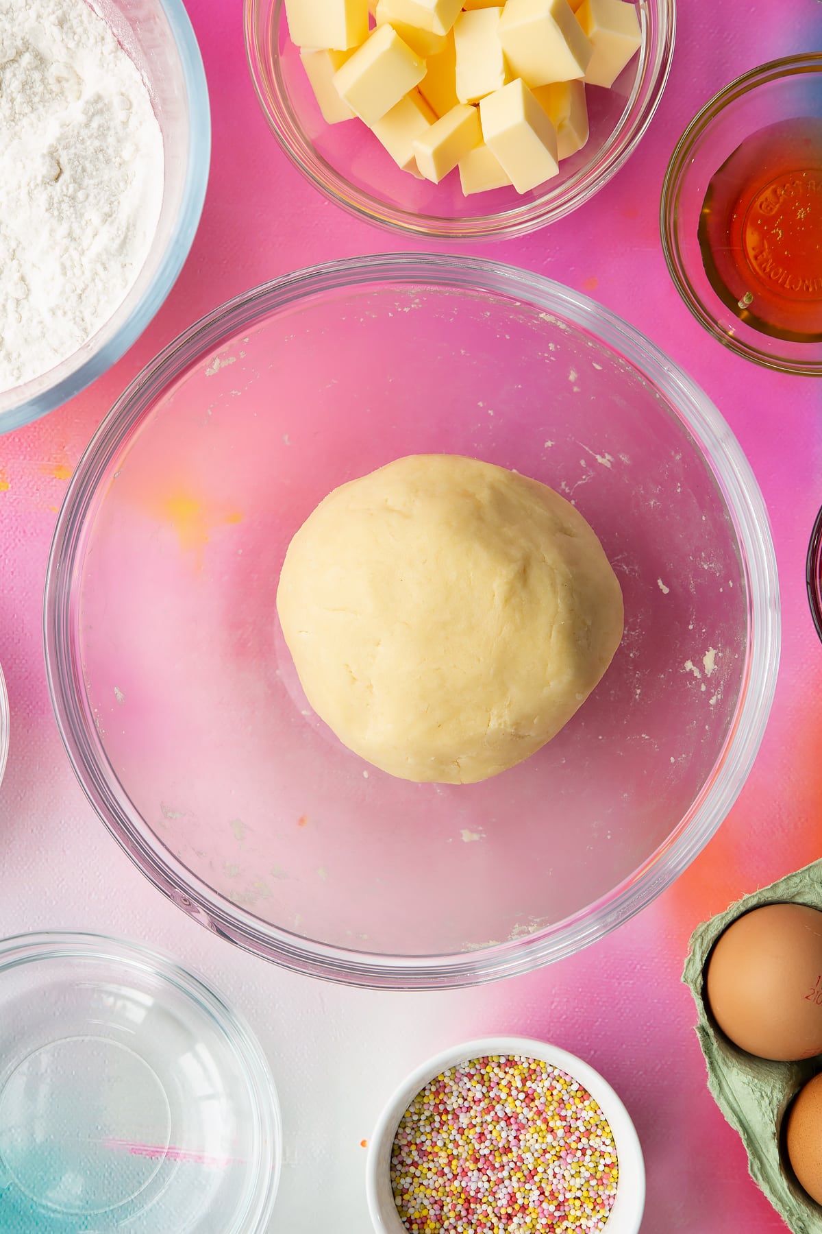 A ball of gluten free pastry in a glass mixing bowl. Ingredients to make gluten free pop tarts surround the bowl.