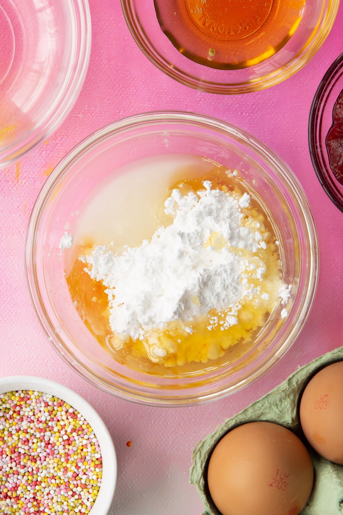 Icing sugar, golden syrup and water in a small bowl. Ingredients to make gluten free pop tarts surround the bowl.