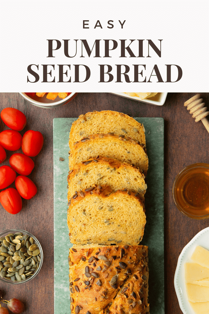 Sliced loaf of pumpkin seed specie on a marble board. Caption reads: Easy pumpkin seed bread.