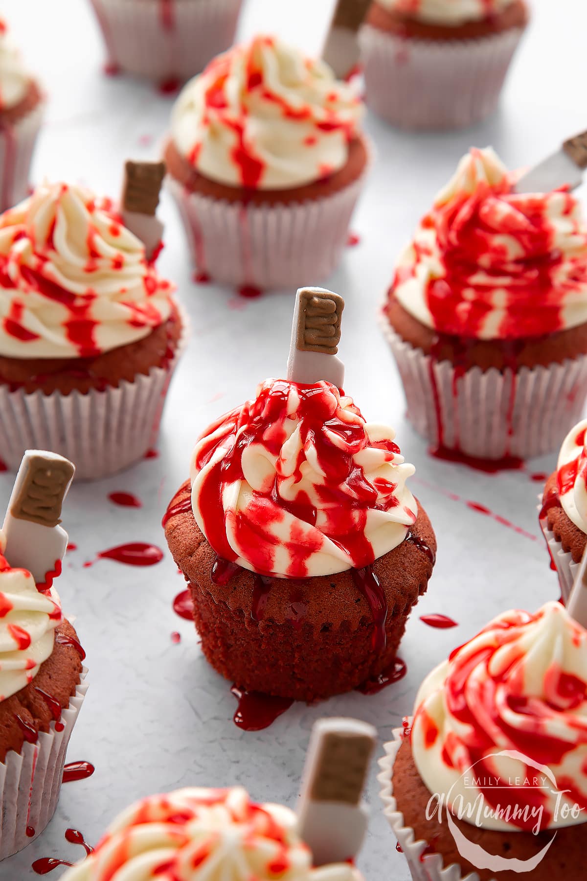 Red velvet Halloween cupcakes, spattered with red syrup. The one in the foreground has been unwrapped.