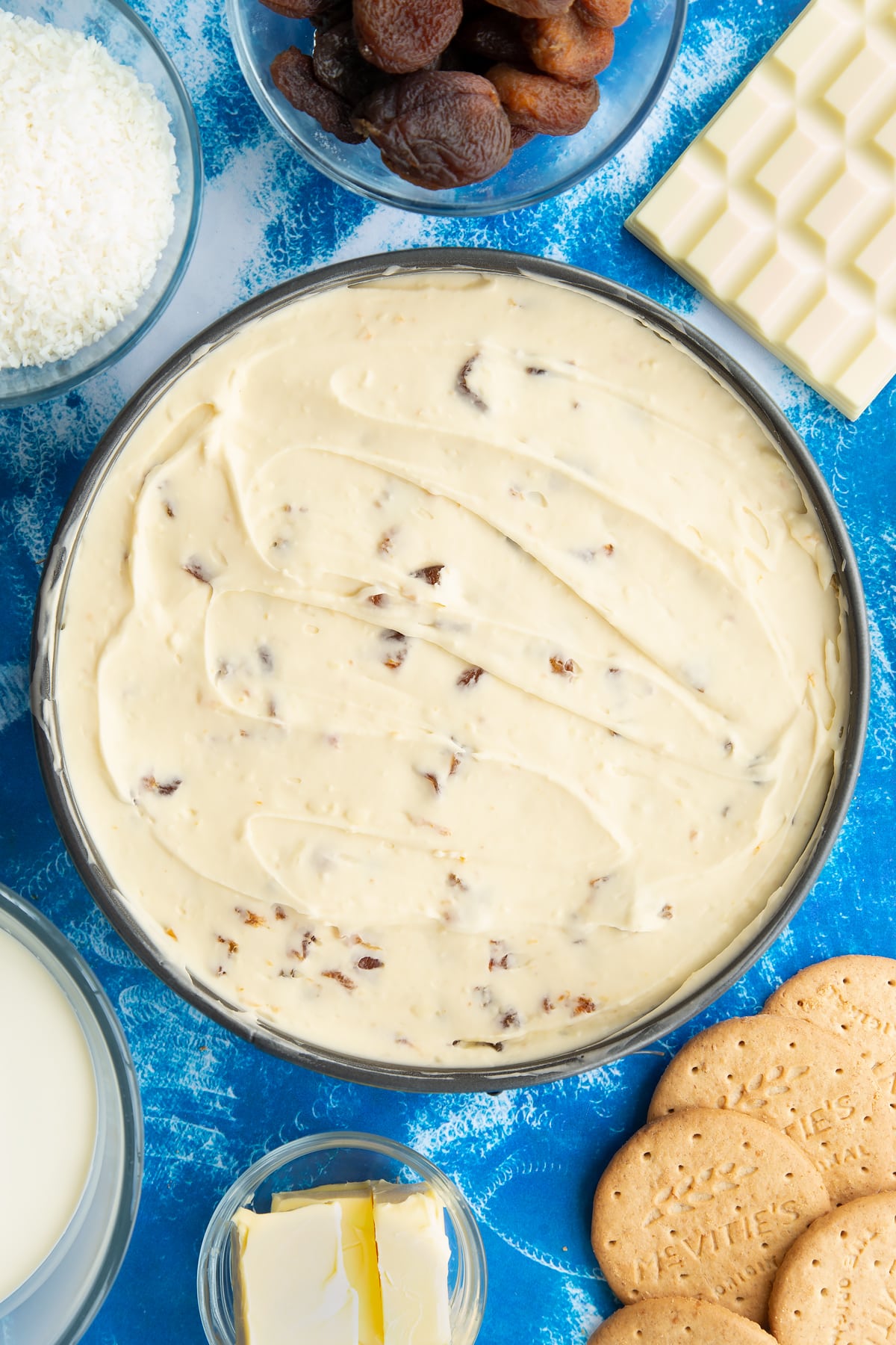 Apricot cheesecake filling in a tin on top of a biscuit base.