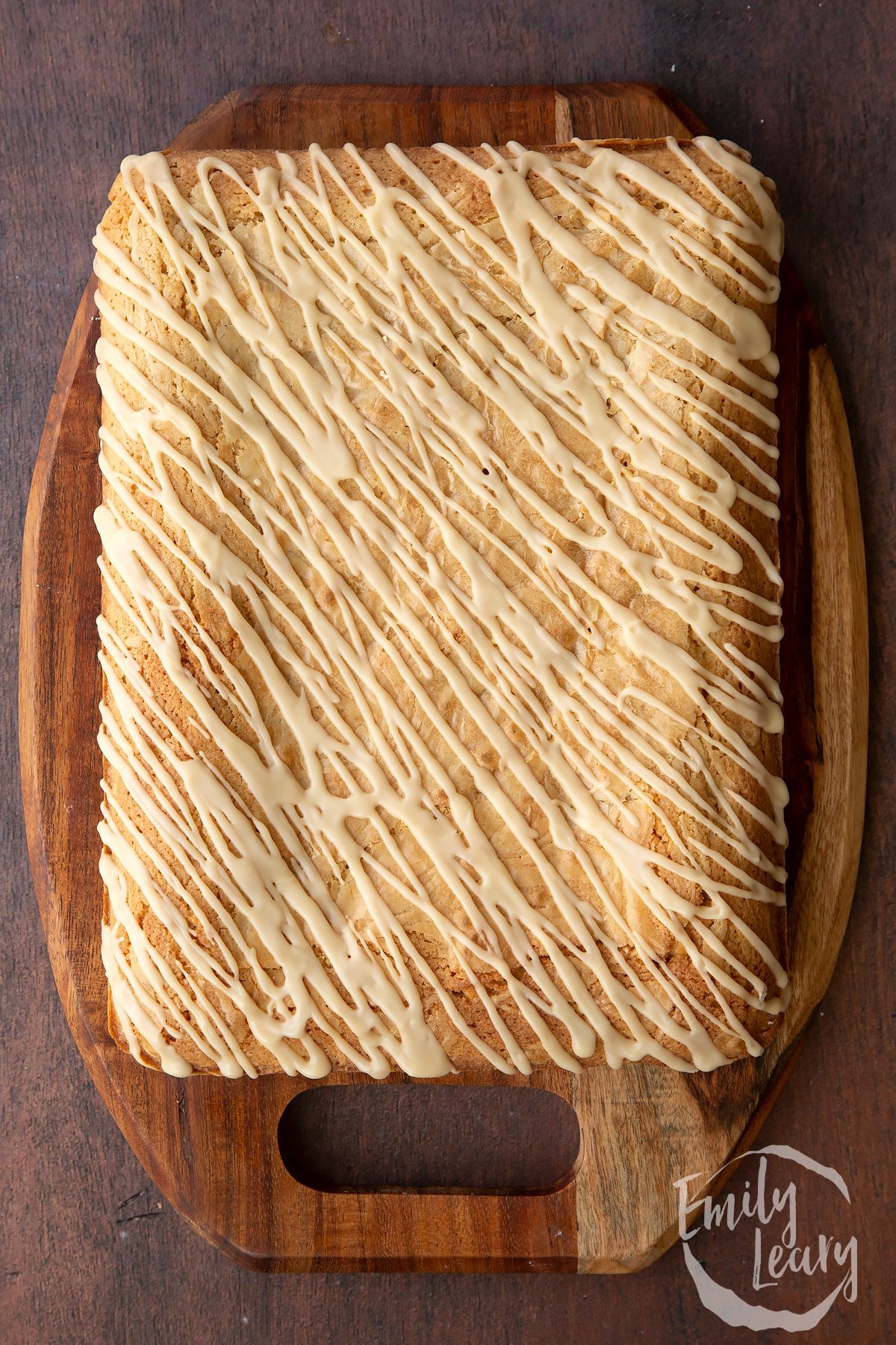 Freshly baked Baileys blondie drizzled with Baileys icing on a wooden board.