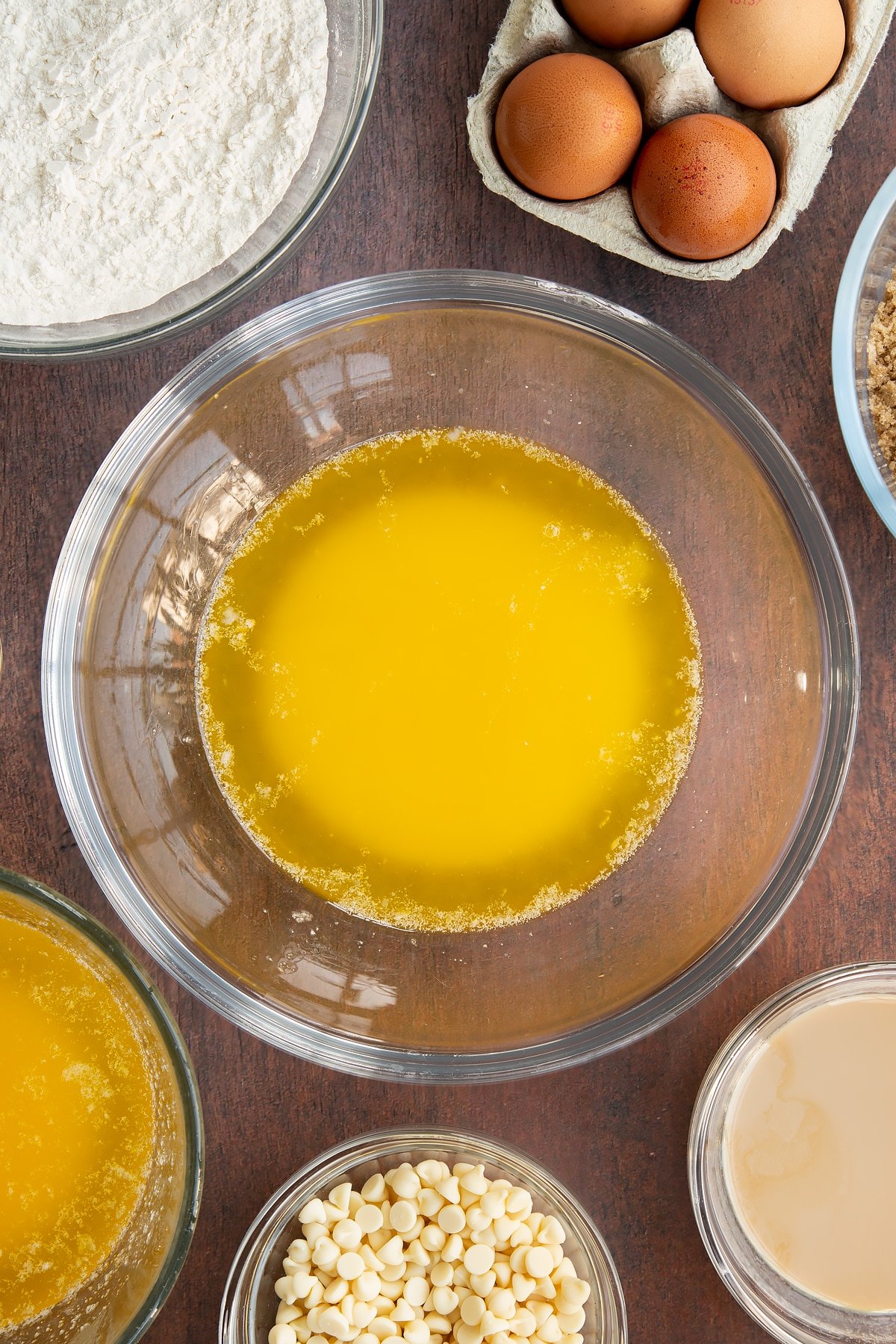 Melted butter in a glass mixing bowl. Ingredients to make Baileys blondies surround the bowl.